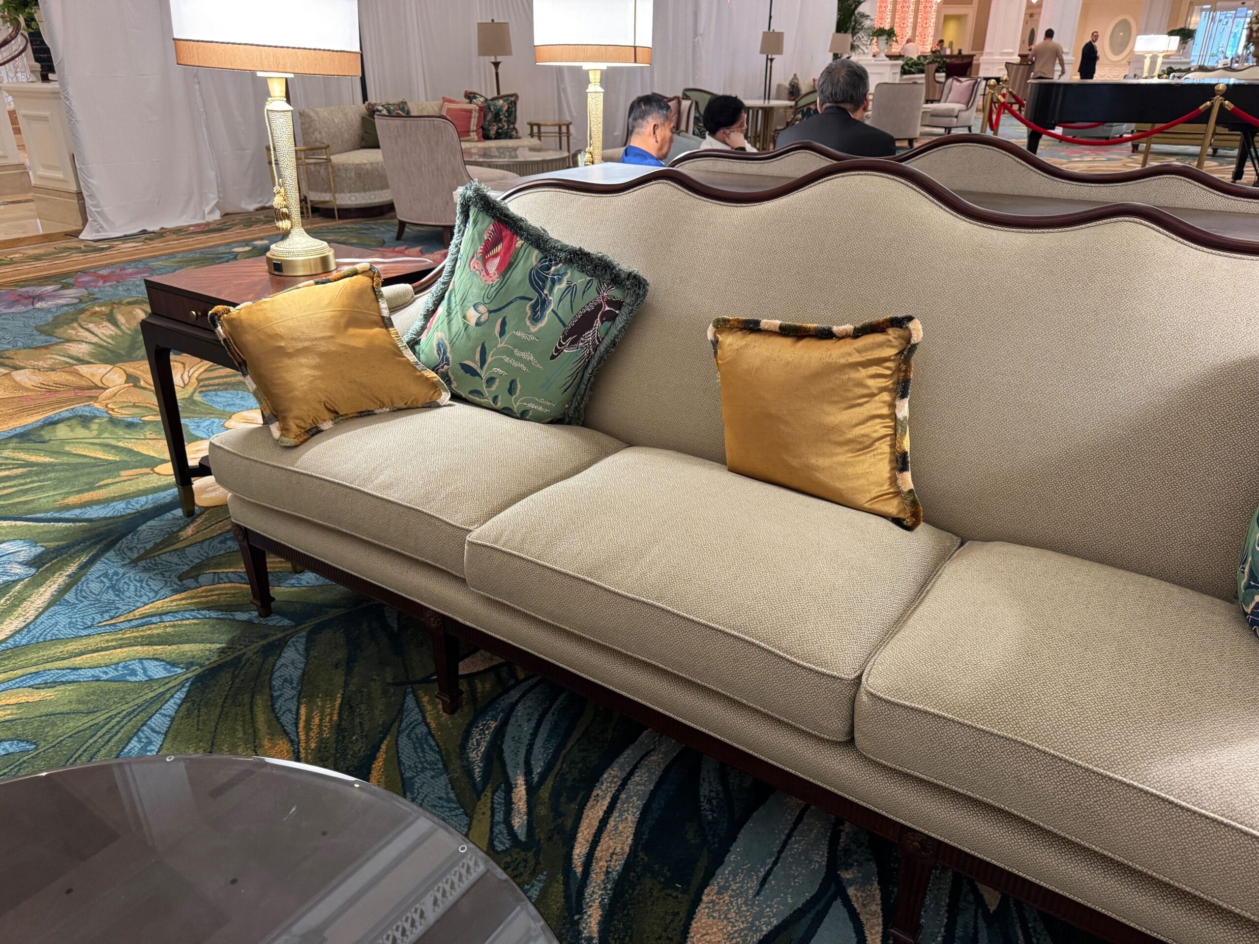 Beige sofa with colorful pillows at Disney's Grand Floridian Resort, reminiscent of Main Street elegance, guests relaxing behind.
