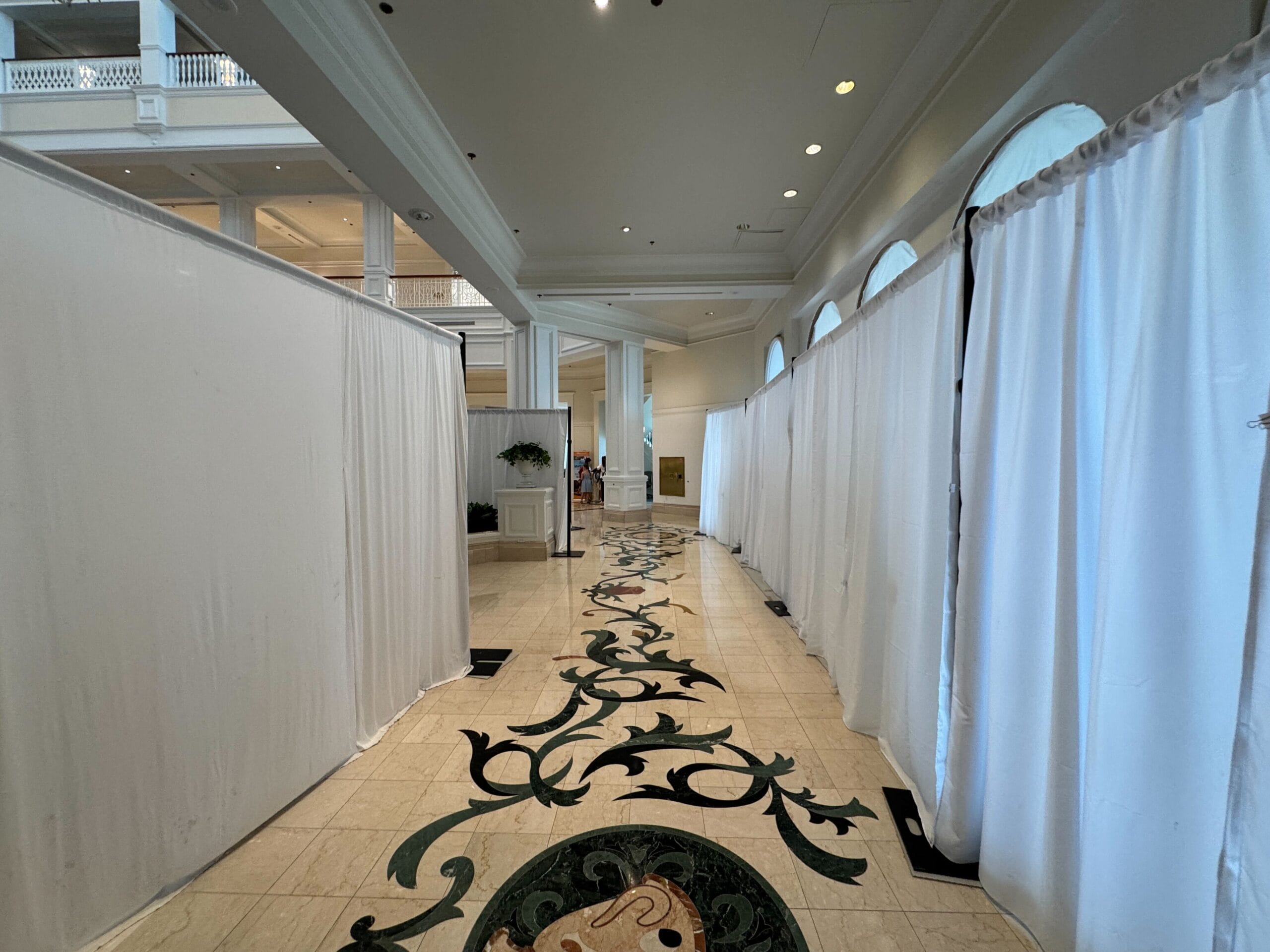 A hallway with elegant tile floors at Disney’s Grand Floridian Resort leads to a sunlit space, echoing Magic Kingdom’s grand style.