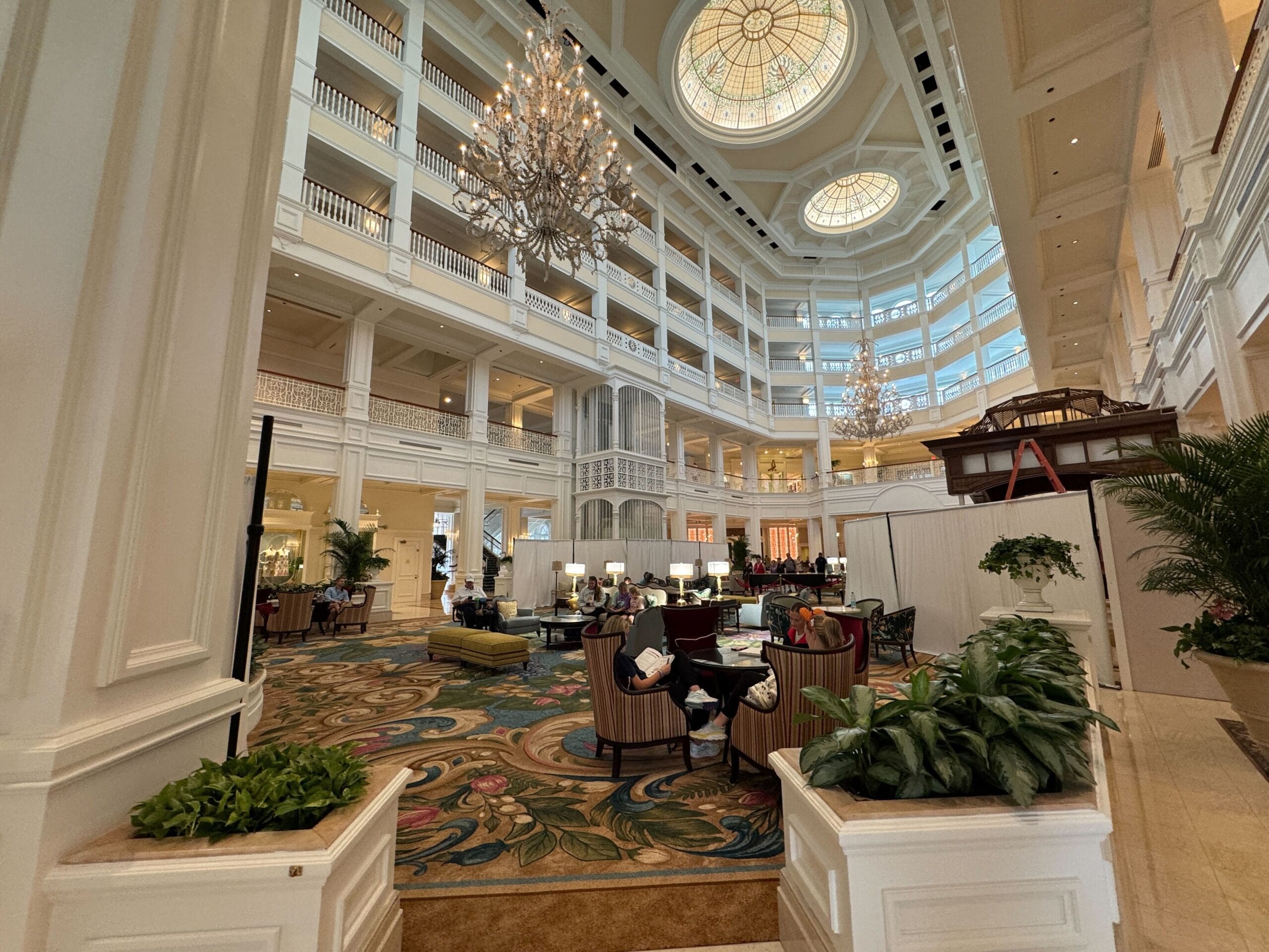 Grand Floridian Resort lobby at Walt Disney World, elegant chandeliers, soaring ceilings, Victorian decor, and plush seating areas.