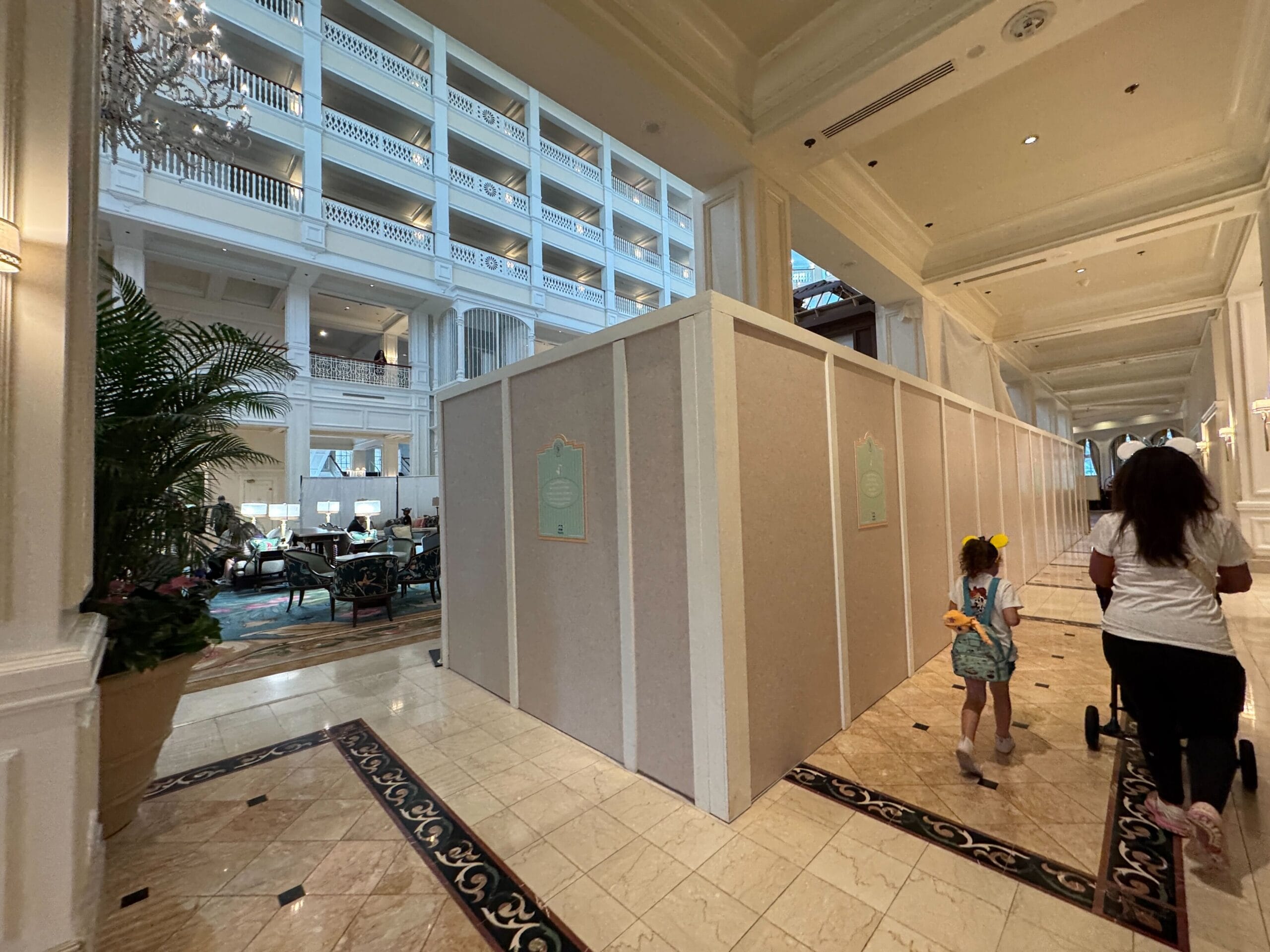 Lobby at Disney's Grand Floridian Resort with refurbishment walls, guests seated, and a child walking, no castle visible.