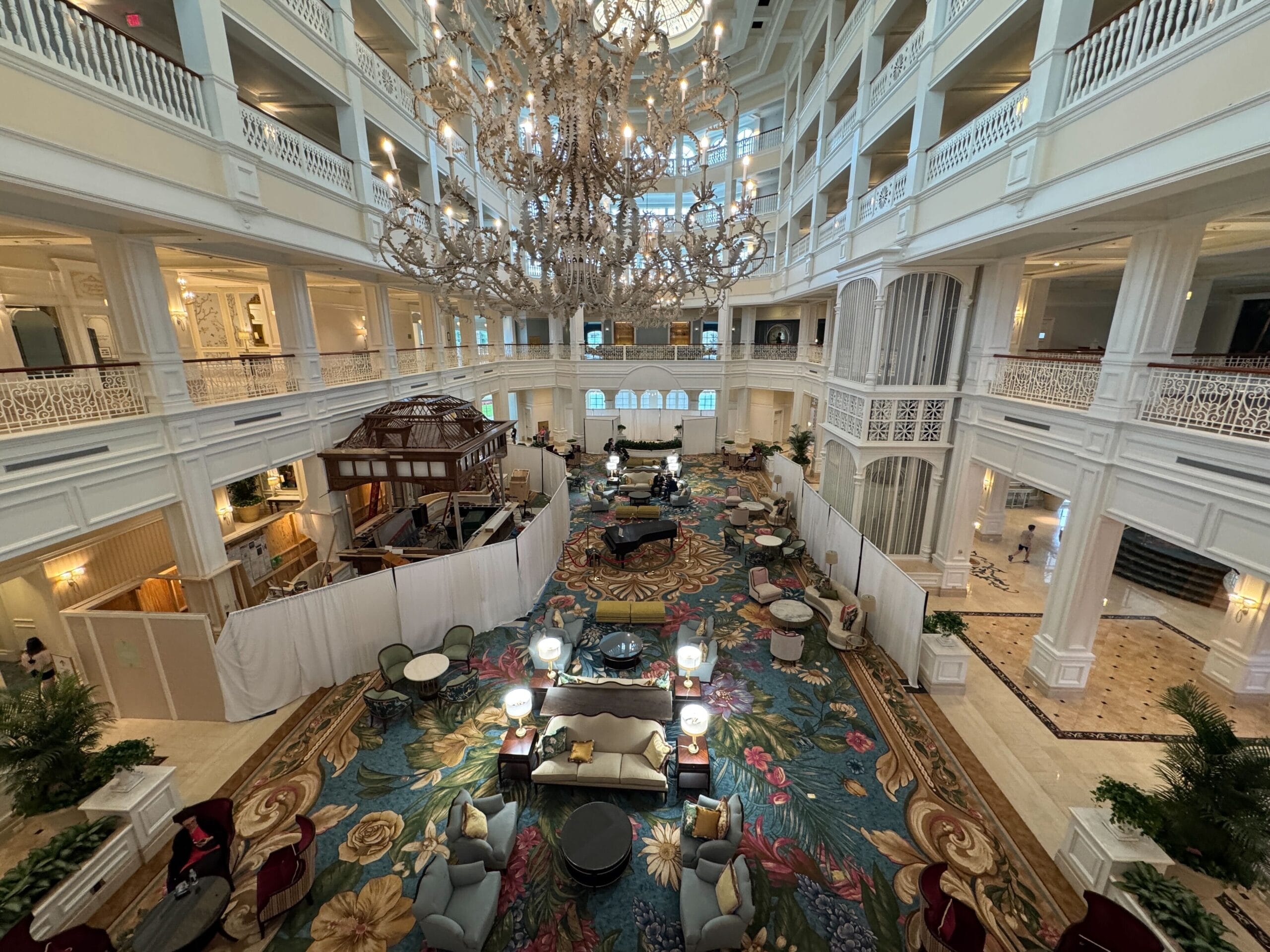 Grand Floridian Resort lobby at Walt Disney World, featuring opulent chandelier, elegant columns, and floral carpet seen from above.