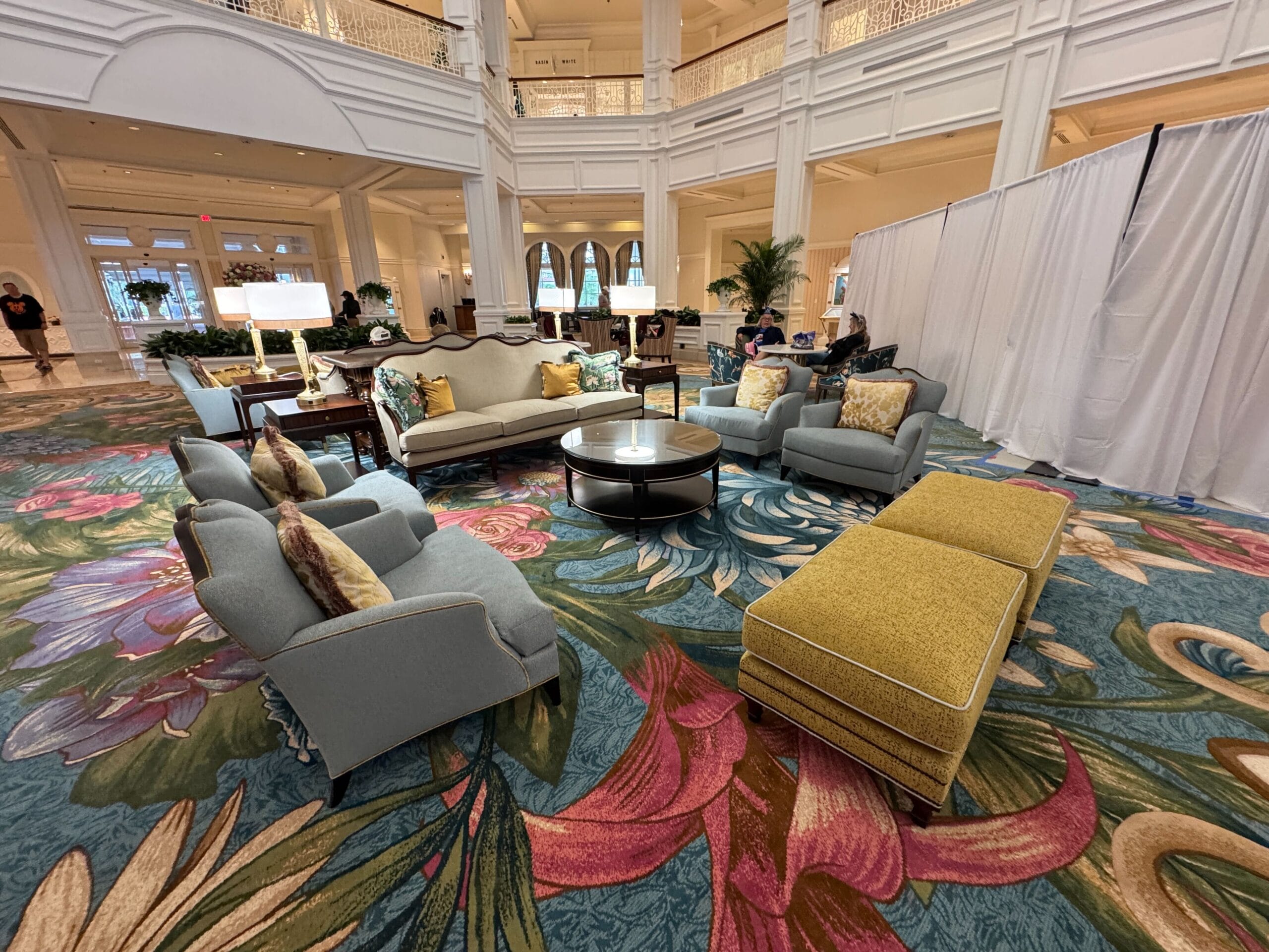 Chic Grand Floridian lobby at Walt Disney World with floral carpet, plush sofas, and bright decor—no castle but classic Disney elegance.