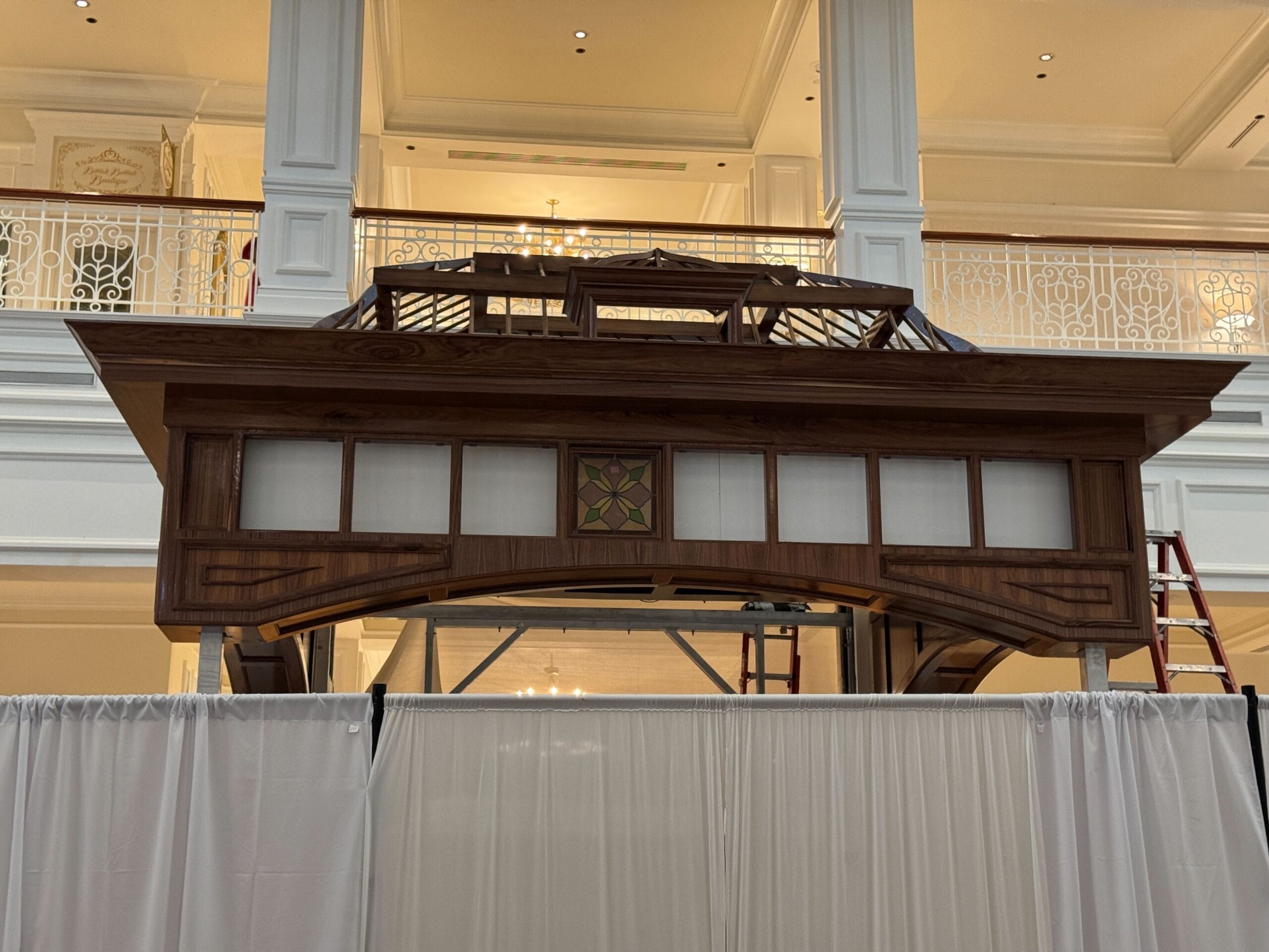A large wooden gazebo under construction inside Disney’s Grand Floridian Resort, surrounded by white curtains and ladders—no castle visible.