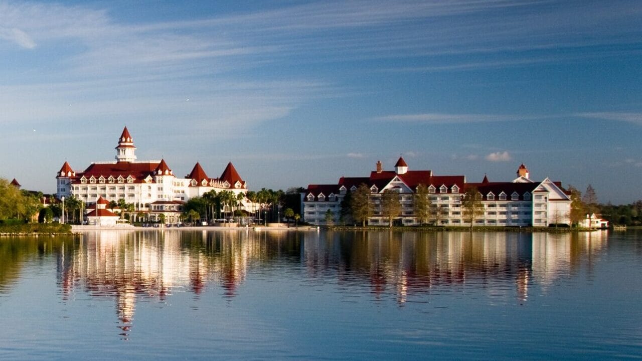 Scenic view of waterfront buildings reflecting on a calm lake under a clear sky, reminiscent of the serene vistas near Walt Disney World.