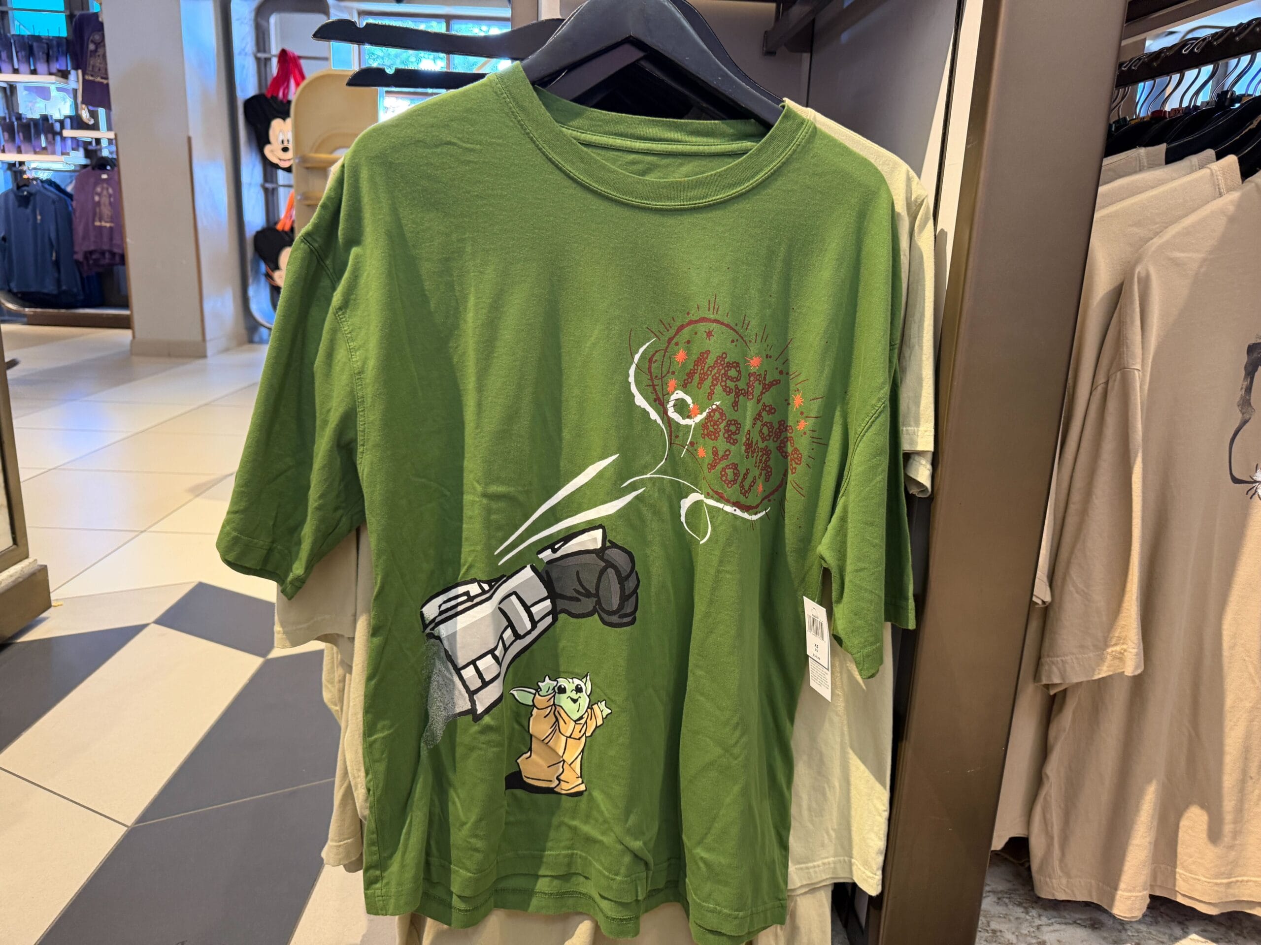 Green T-shirt featuring Baby Yoda and Mandalorian fist bump—great holiday choice for Disney Parks fans, any castle or location!
