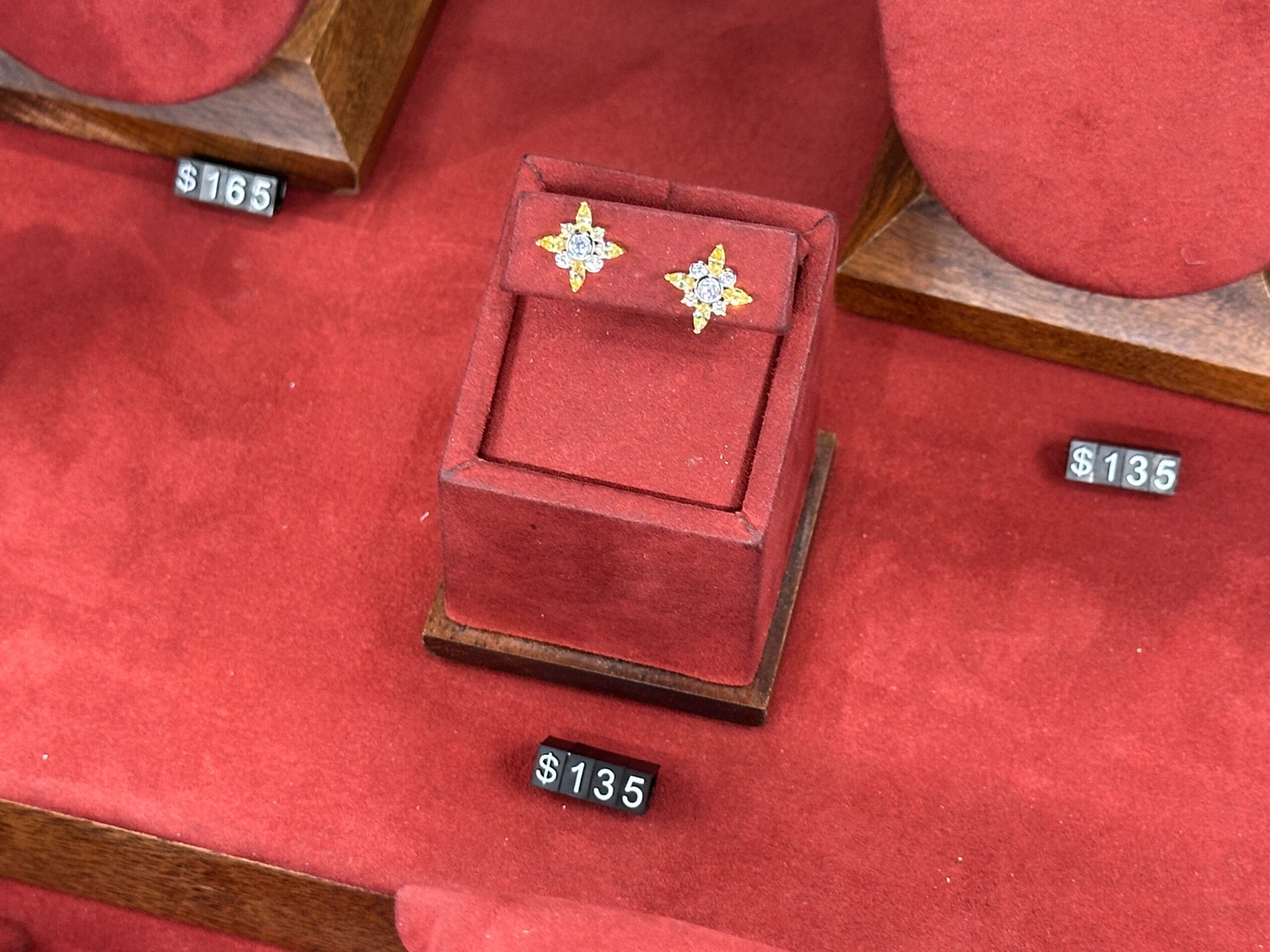 A pair of star-shaped earrings on a red velvet stand with a $135 price tag, reminiscent of jewelry found at Disney parks boutiques.