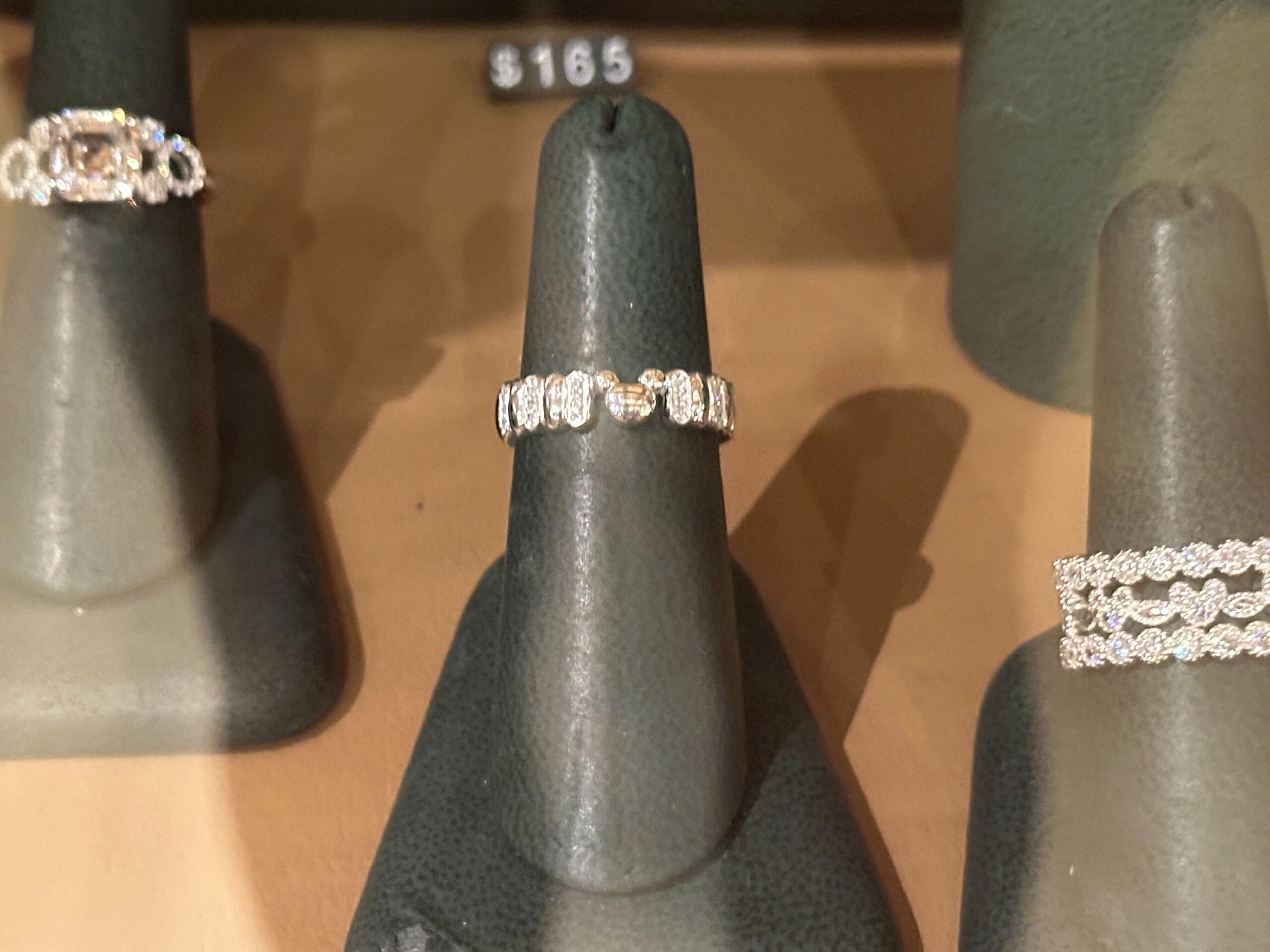 A sparkling diamond ring showcased between two others, priced at $165—just like treasures found in Walt Disney World shops.