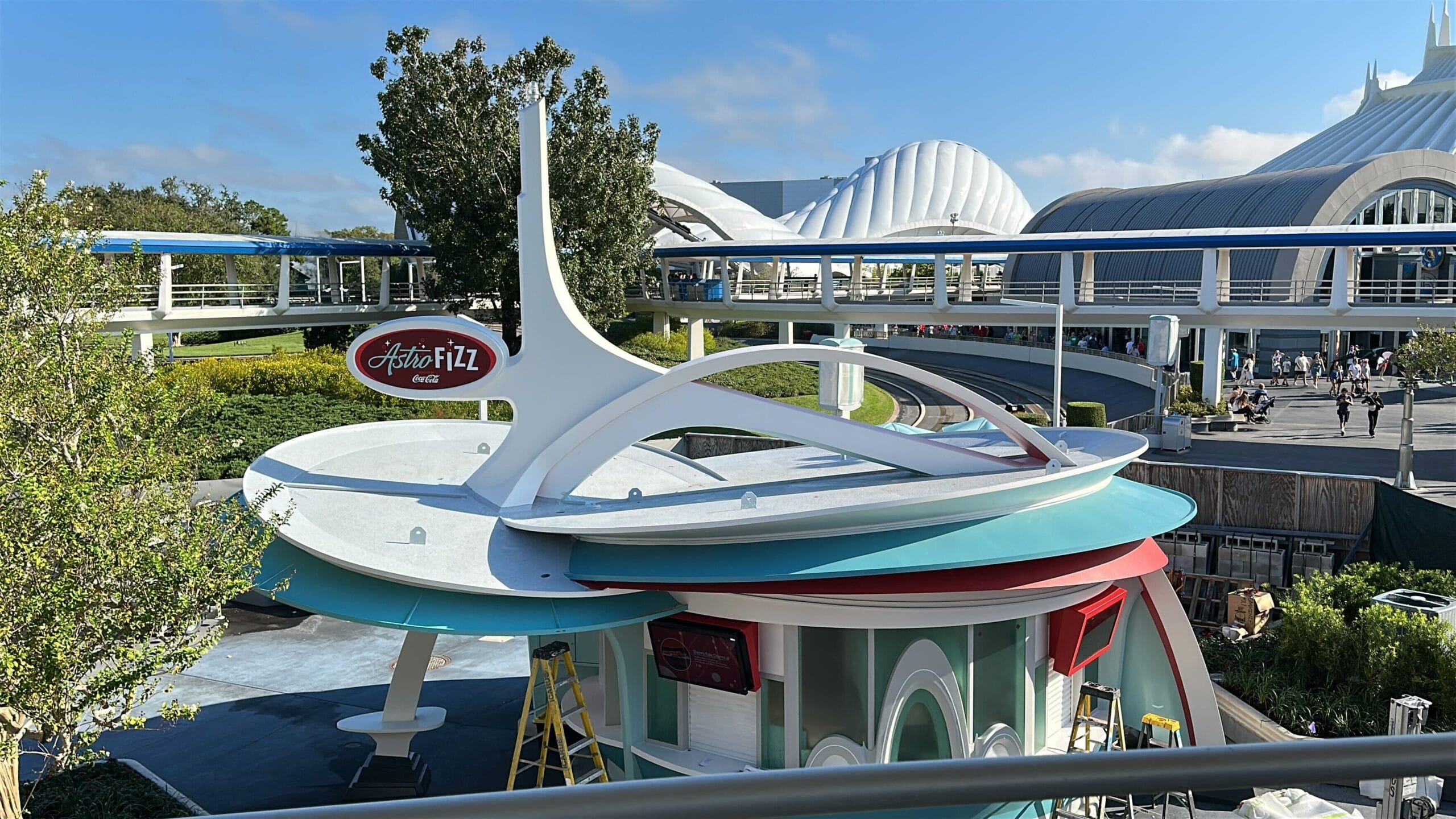 A Walt Disney Park’s retro-style round Astro Orbiter building, with red signage, white arches, and Tomorrowland-inspired features.