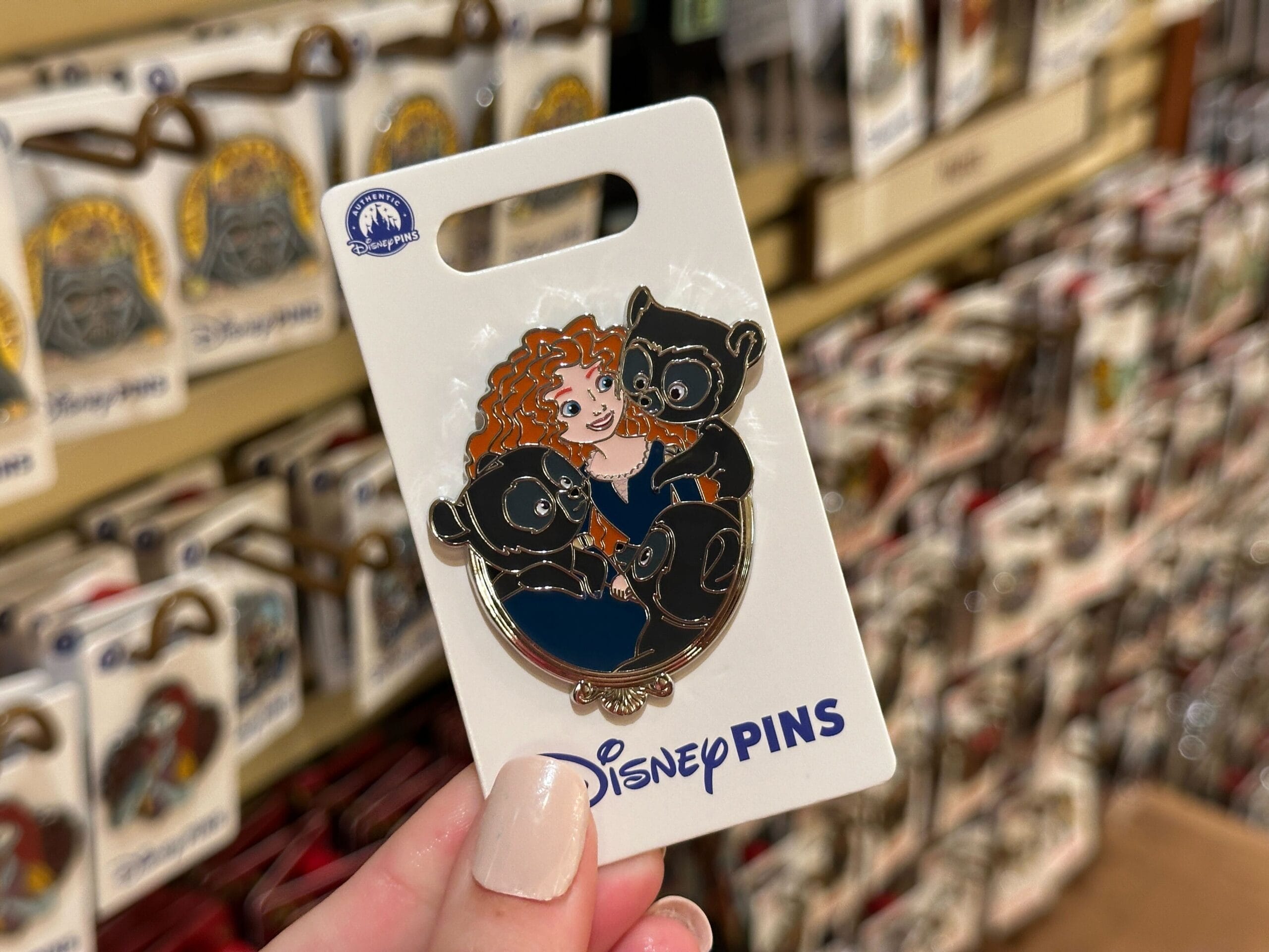 A hand displays a Disney Princess Sidekicks Pin of Merida with three bear cubs from "Brave" at Walt Disney World, not near the castle.