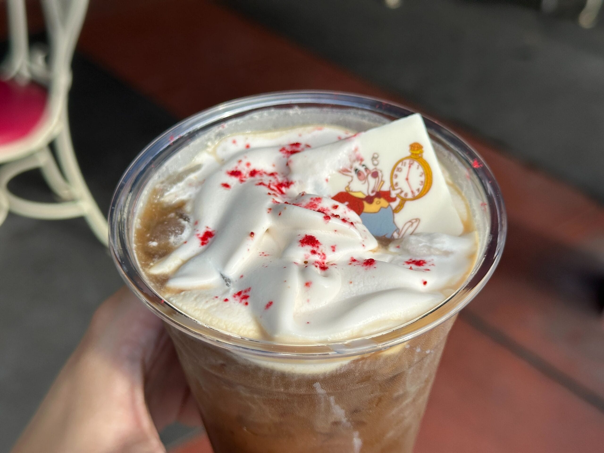 White Rabbit Cold Brew: Iced coffee with whipped cream, red sprinkles, and a white chocolate rabbit styled after Magic Kingdom decor.