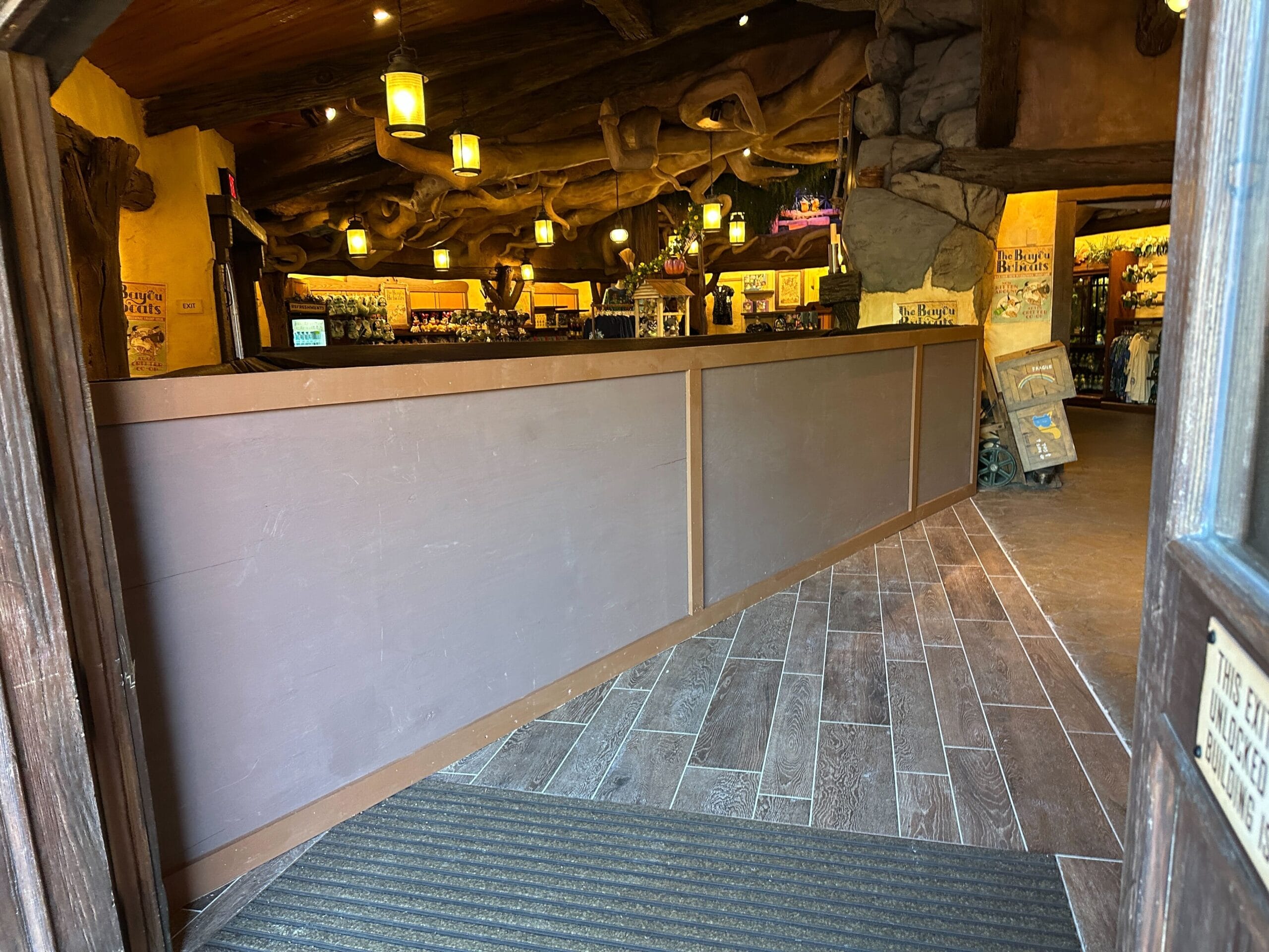 Long wooden counter at Disney World's Critter Co-Op gift shop, featuring warm lighting and new flooring—no castle in view here.