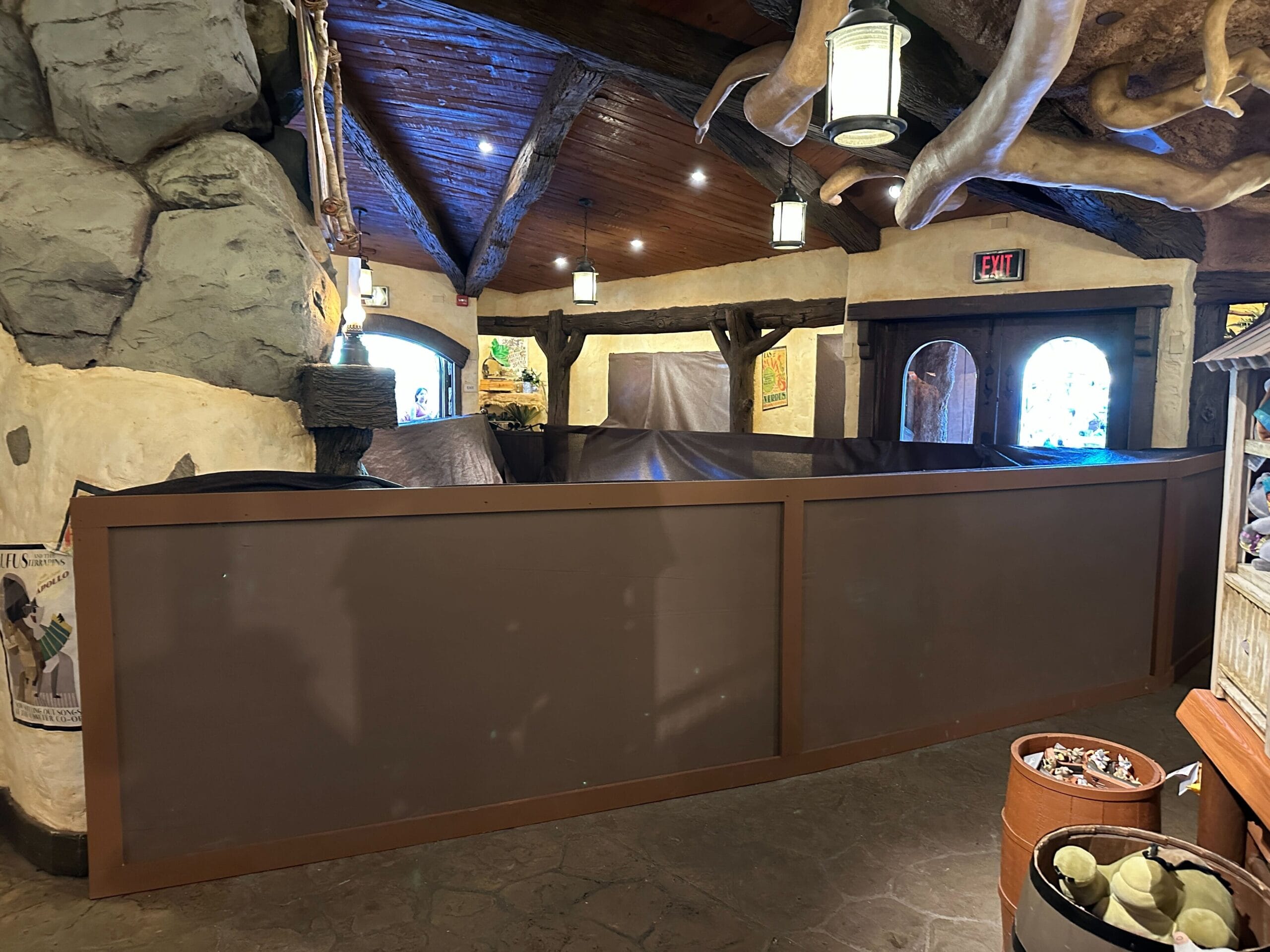 A section of Critter Co-Op at a Disney park is closed with brown walls for floor work beneath wooden beams and bright lighting.