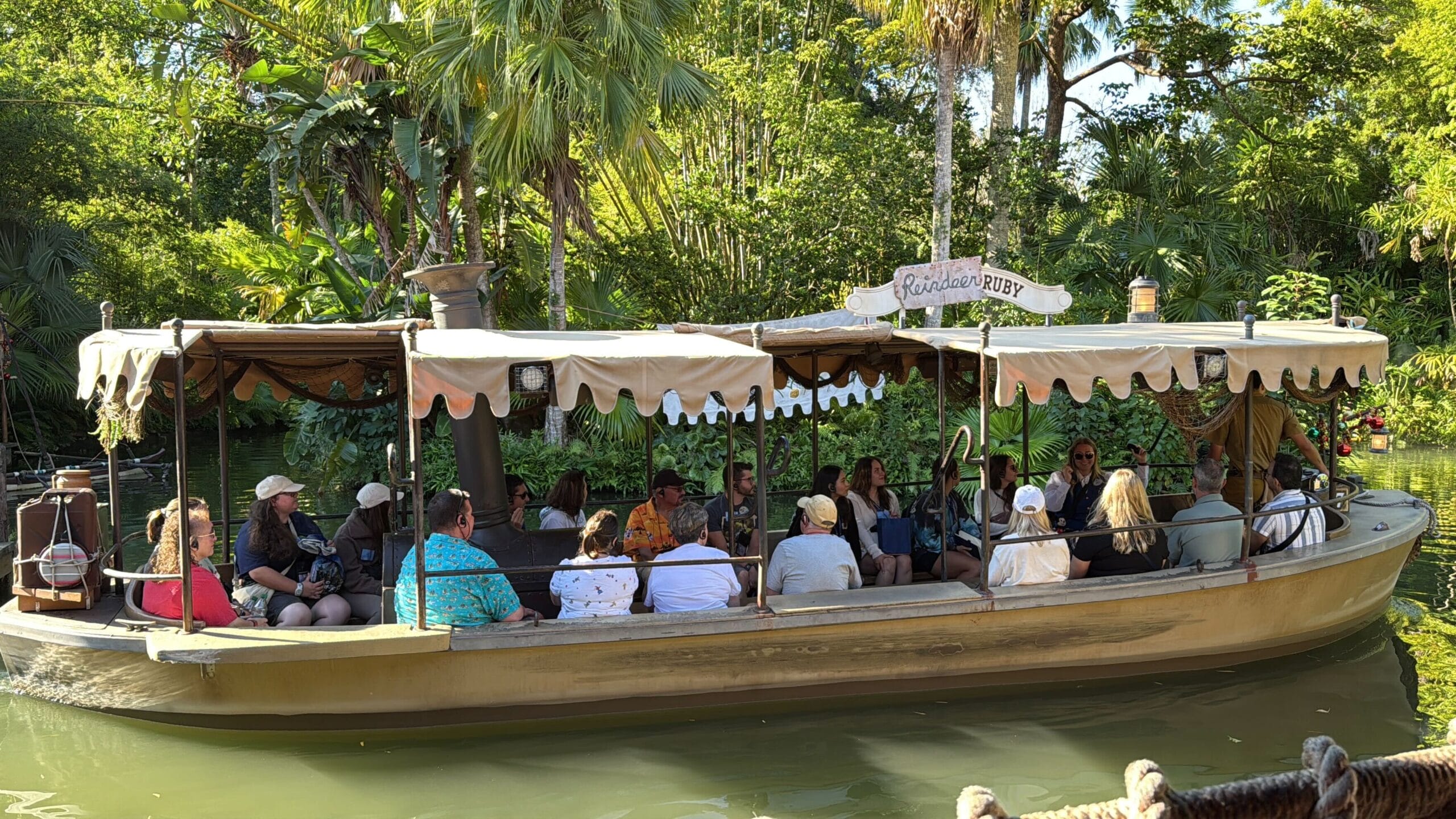 Guests aboard a boat glide through tropical foliage on Magic Kingdom's Jingle Cruise, unique to Walt Disney World in its setting.