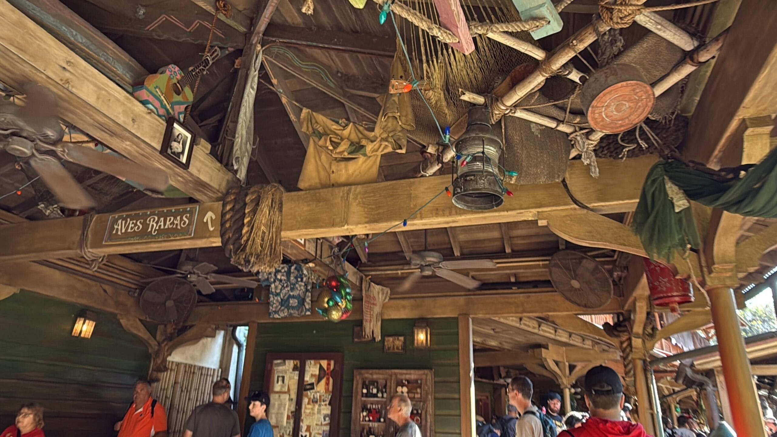 A nautical-themed interior at Magic Kingdom's Jingle Cruise, featuring nets, ropes, lanterns, and guests below