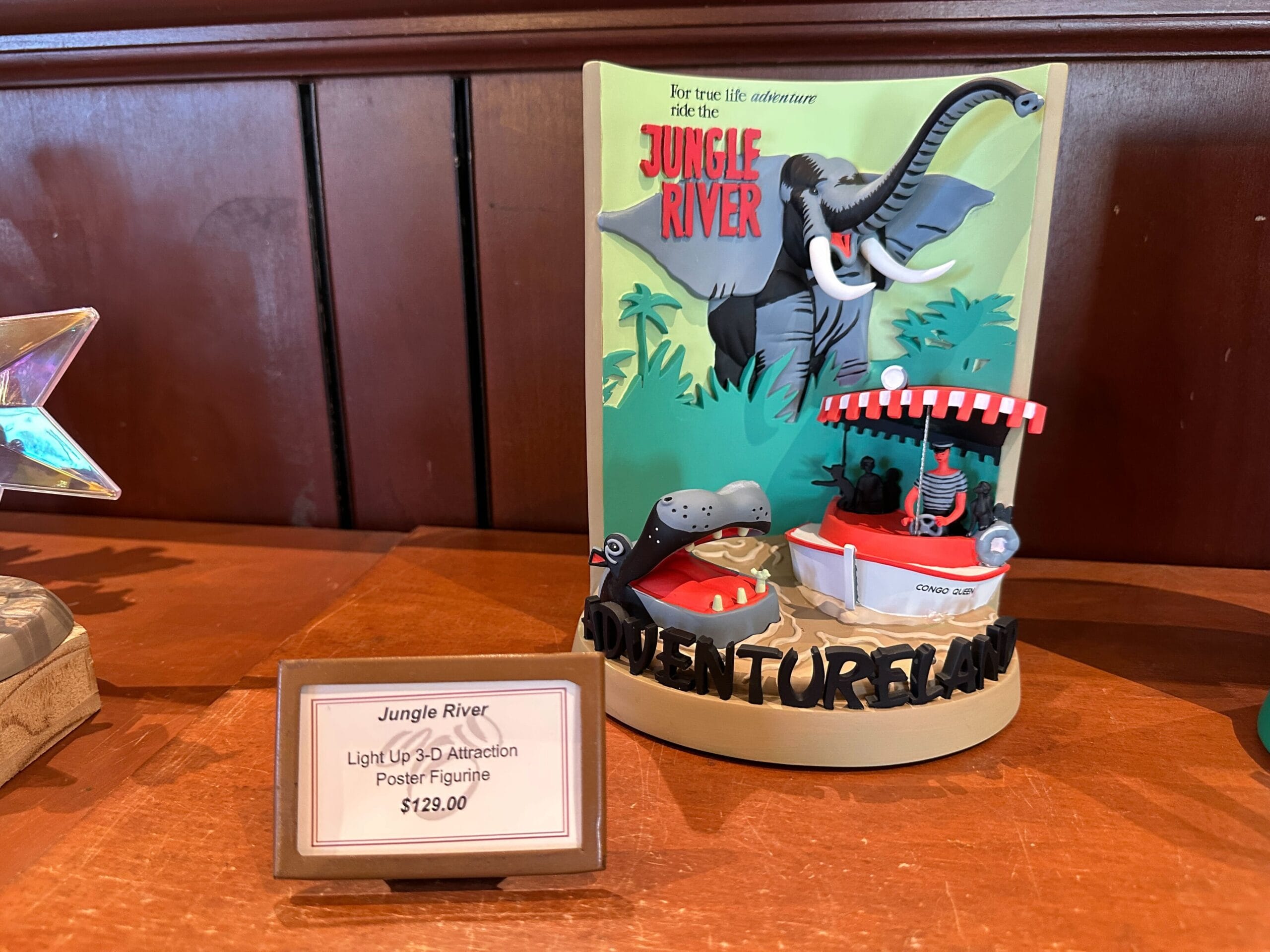 Light-up Jungle Cruise 3-D figurine with elephant, hippo, and boat for $129.00 on a wooden shelf.