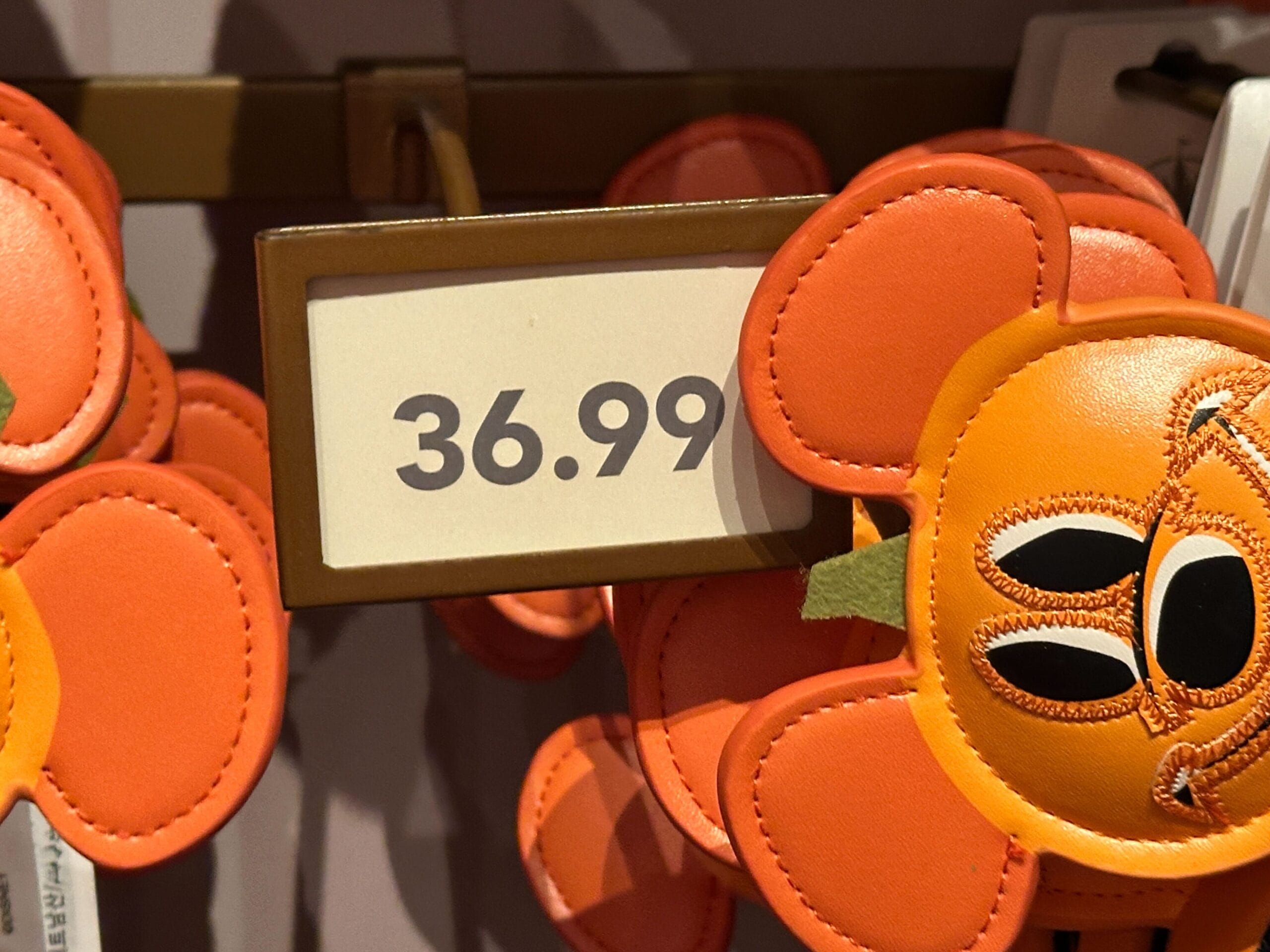 A $36.99 price tag sits above orange cartoon flower Disney World ear headbands, a playful park accessory seen across Disney parks.