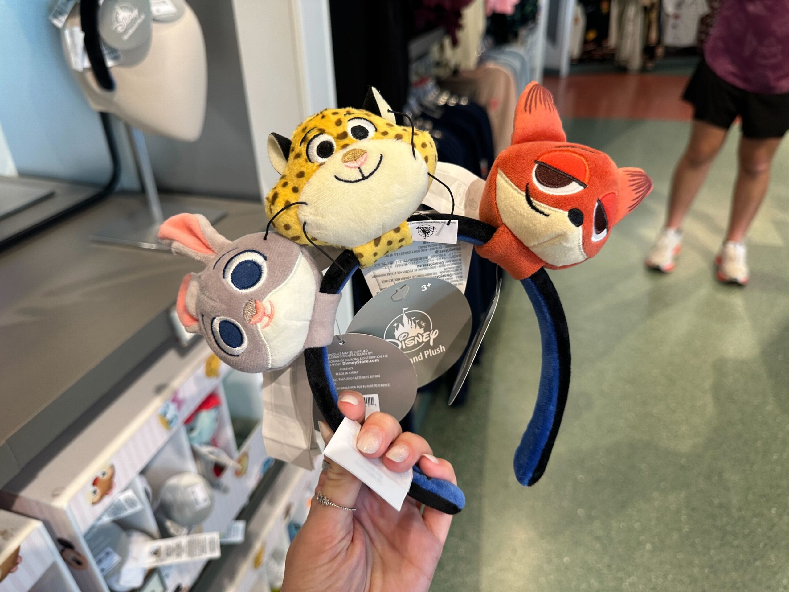 A hand displays a Zootopia plush headband at Disney World, with Cinderella Castle (taller than Disneyland’s) in the blurred background.