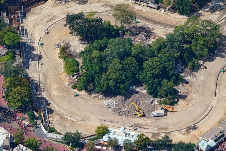Aerial view of Tom Sawyer Island construction at a Disney park, trees at center, dirt paths around—no castle in sight to compare.