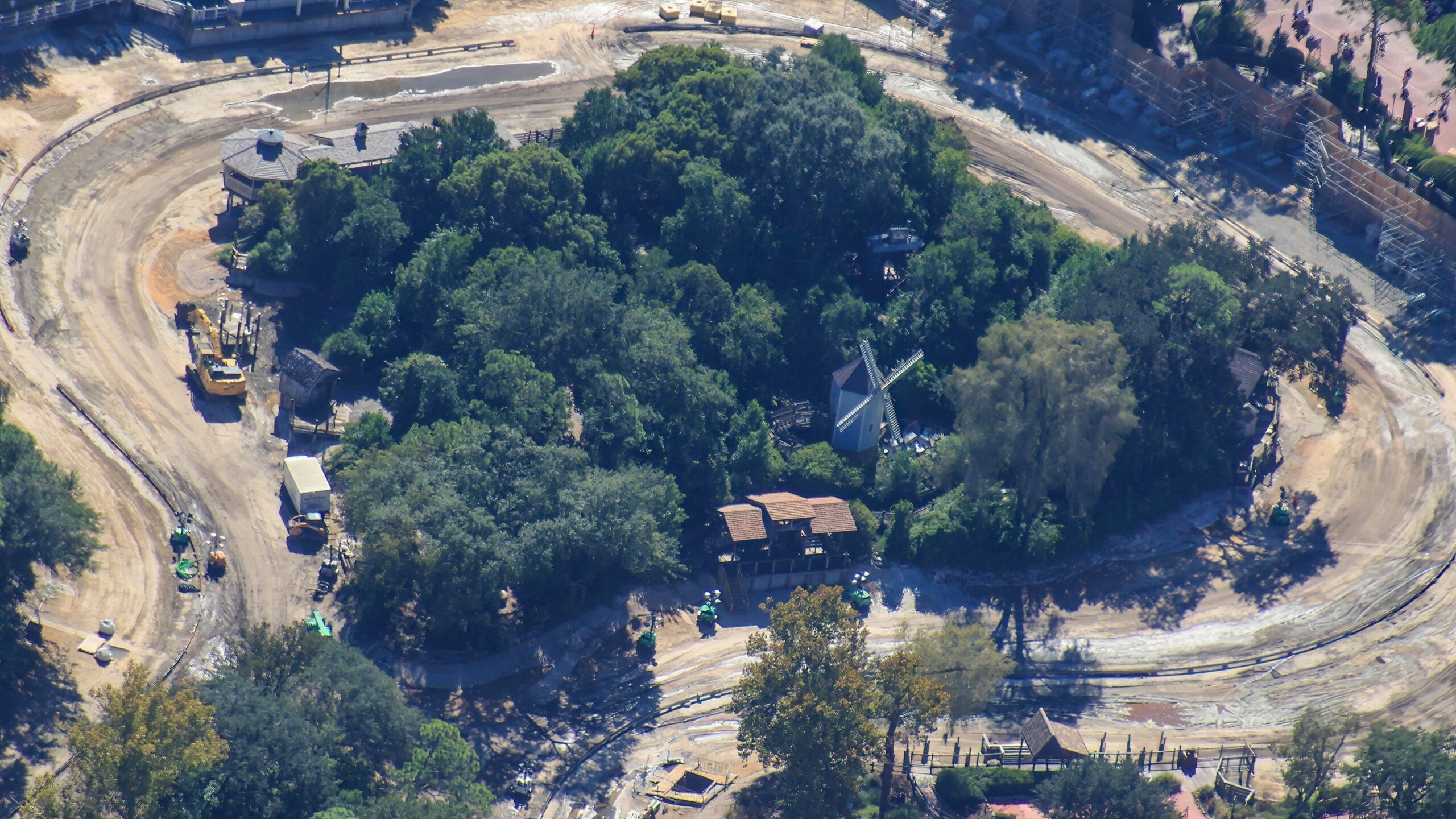 Aerial view of Tom Sawyer Island at a Disney park showing construction, small buildings, dirt roads, and lush trees—no castle visible.