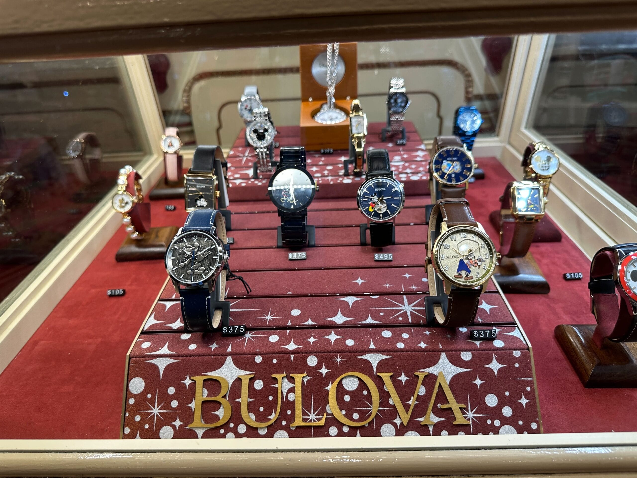 A display case of Bulova watches on a red, star-patterned stand, evoking Disney magic with Limited Edition pieces and price tags.