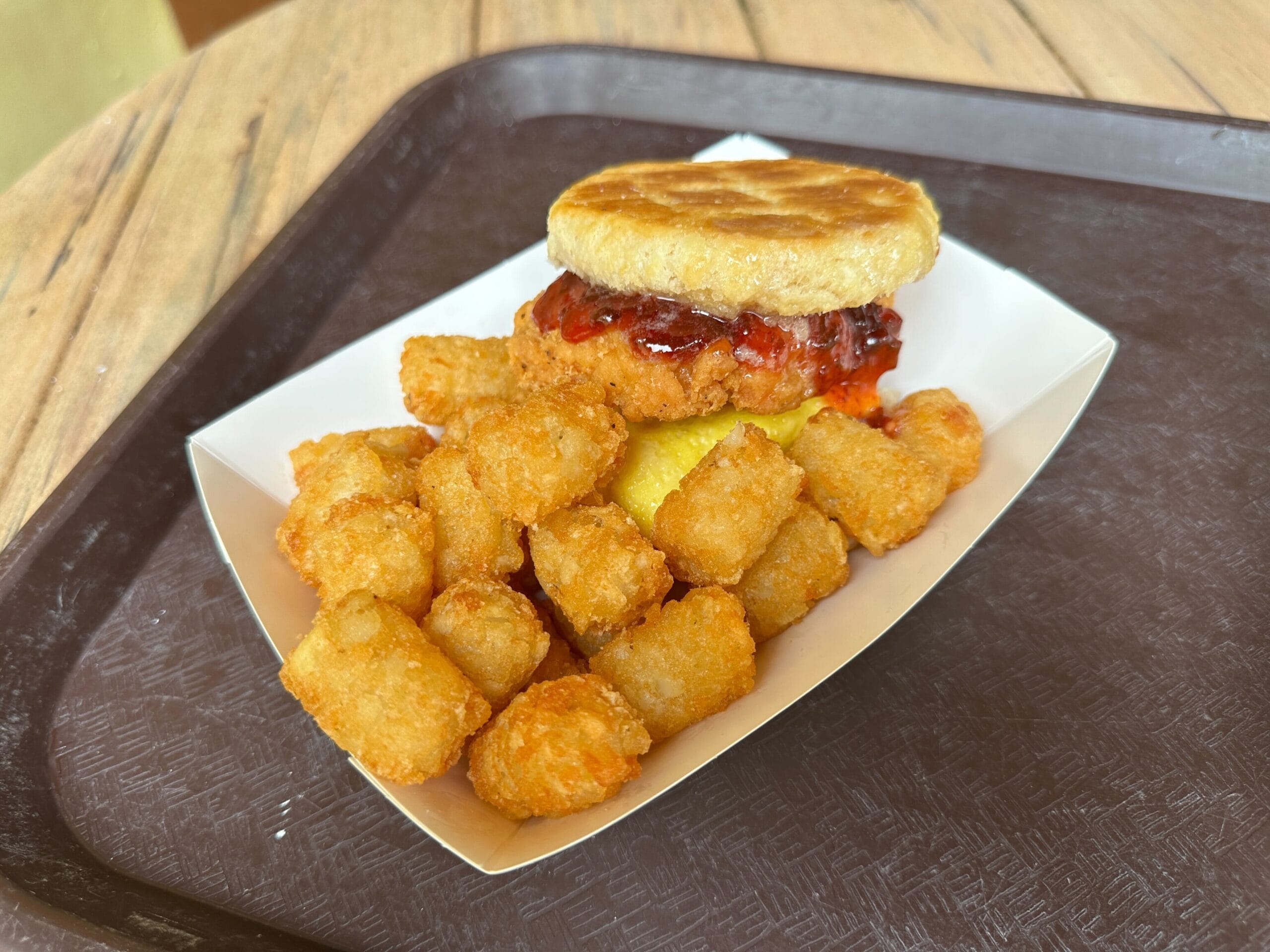 Golden Oak Outpost breakfast tray in Magic Kingdom with tater tots, biscuit, fried chicken, cheese, and sauce—no castle view here.