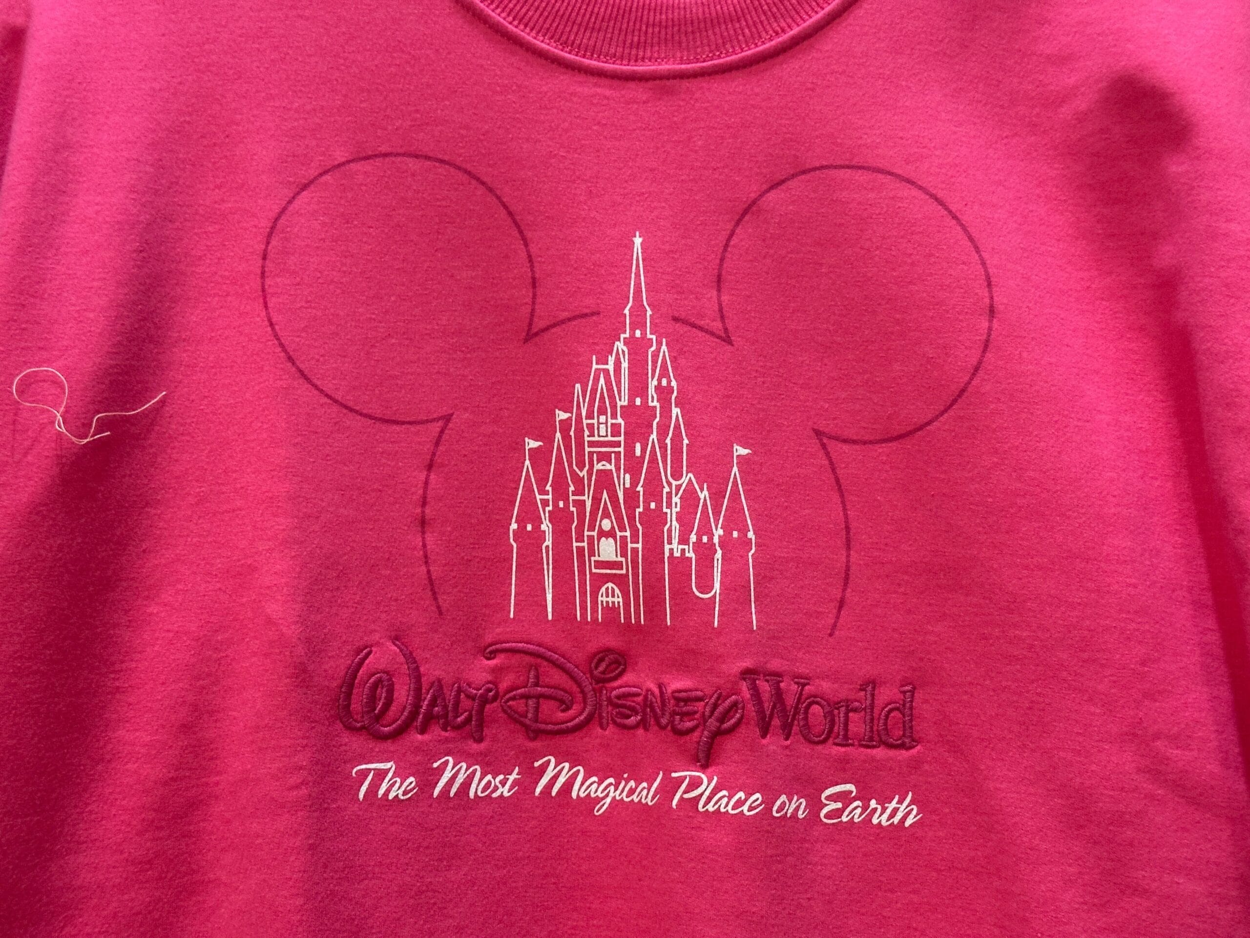 Pink shirt features Cinderella Castle, distinct to Walt Disney World, inside Mickey ears, with text: "Walt Disney World, The Most Magical Place on Earth.