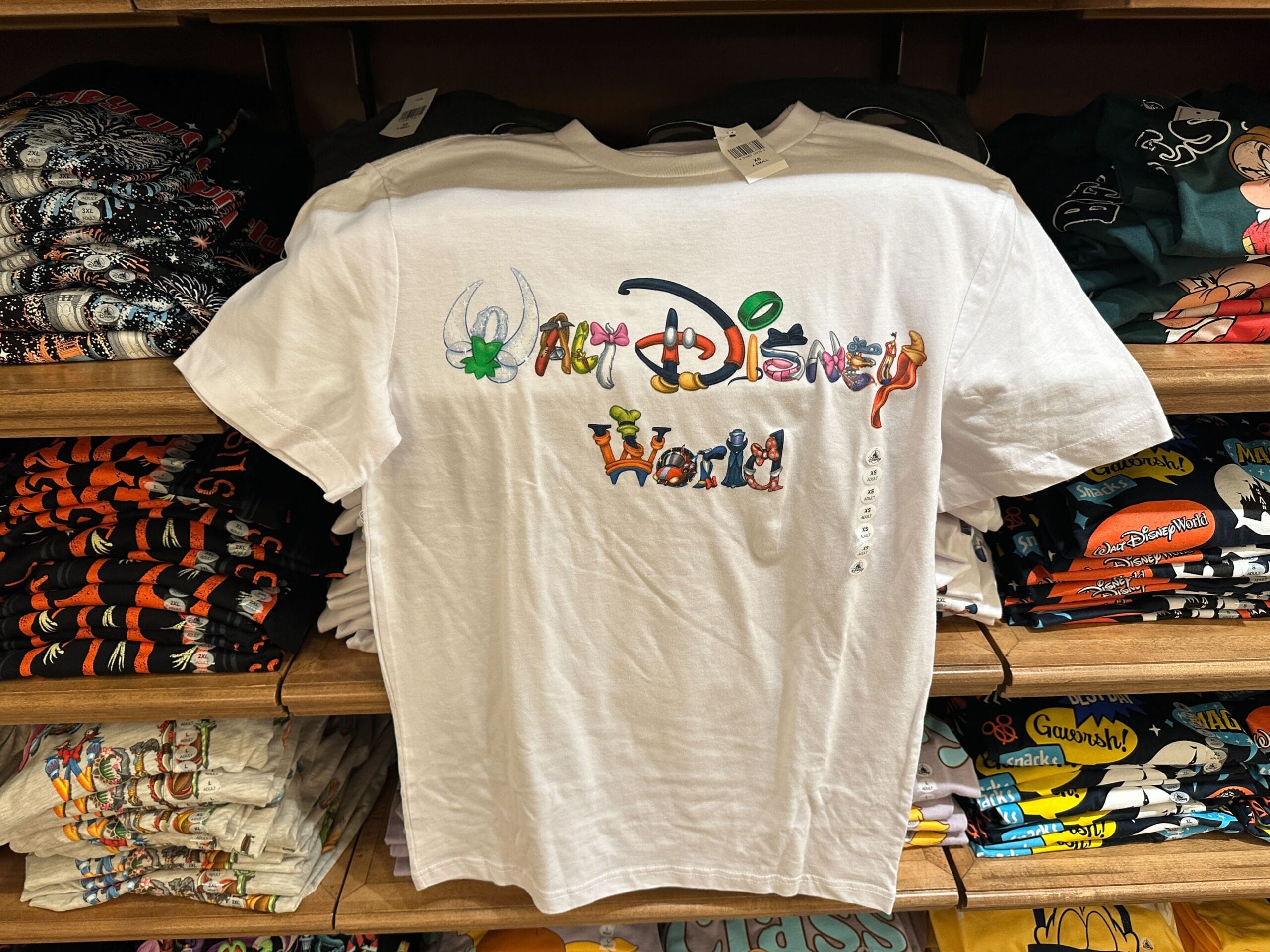 A white T-shirt reads "Walt Disney World," each letter styled as a Disney character, reminiscent of park signage in Florida.