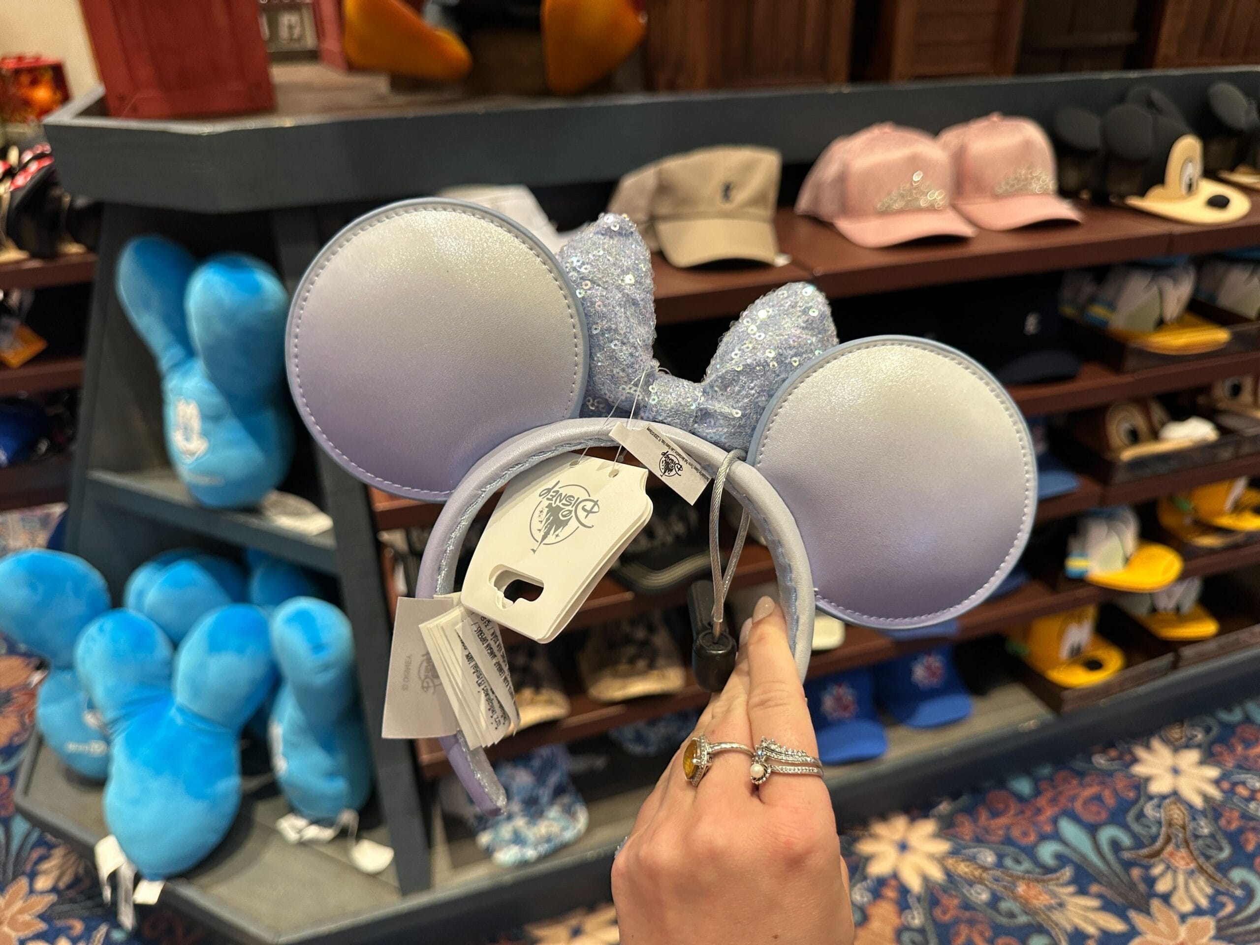 A hand displays a Disney Pearly Blue Ear Headband inside Port Orleans Riverside’s store, with resort shelves visible behind.