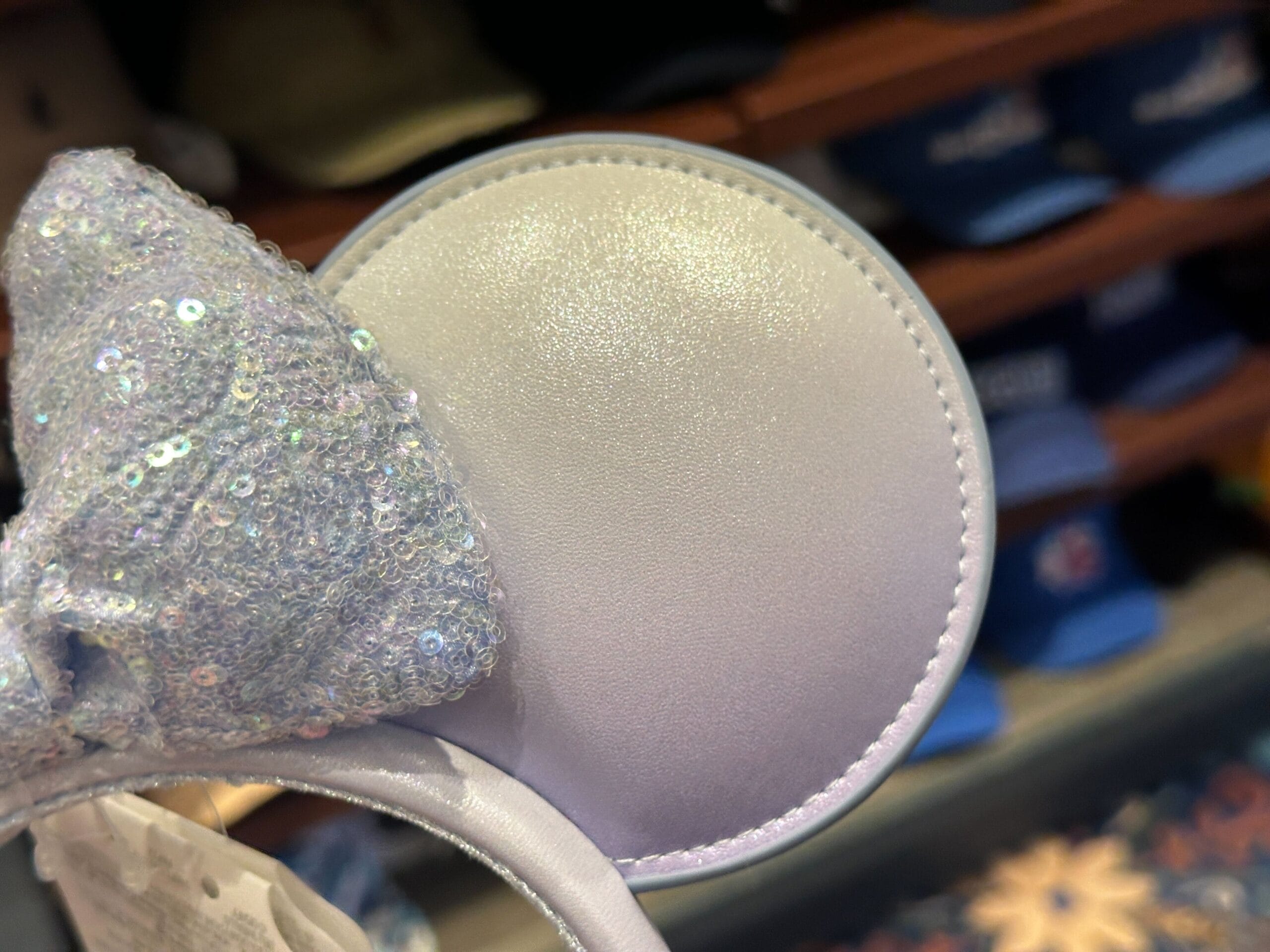 Sparkly Pearly Blue Ear Headband with sequin bow on display at a Disney store, reminiscent of fashionable parks merchandise.