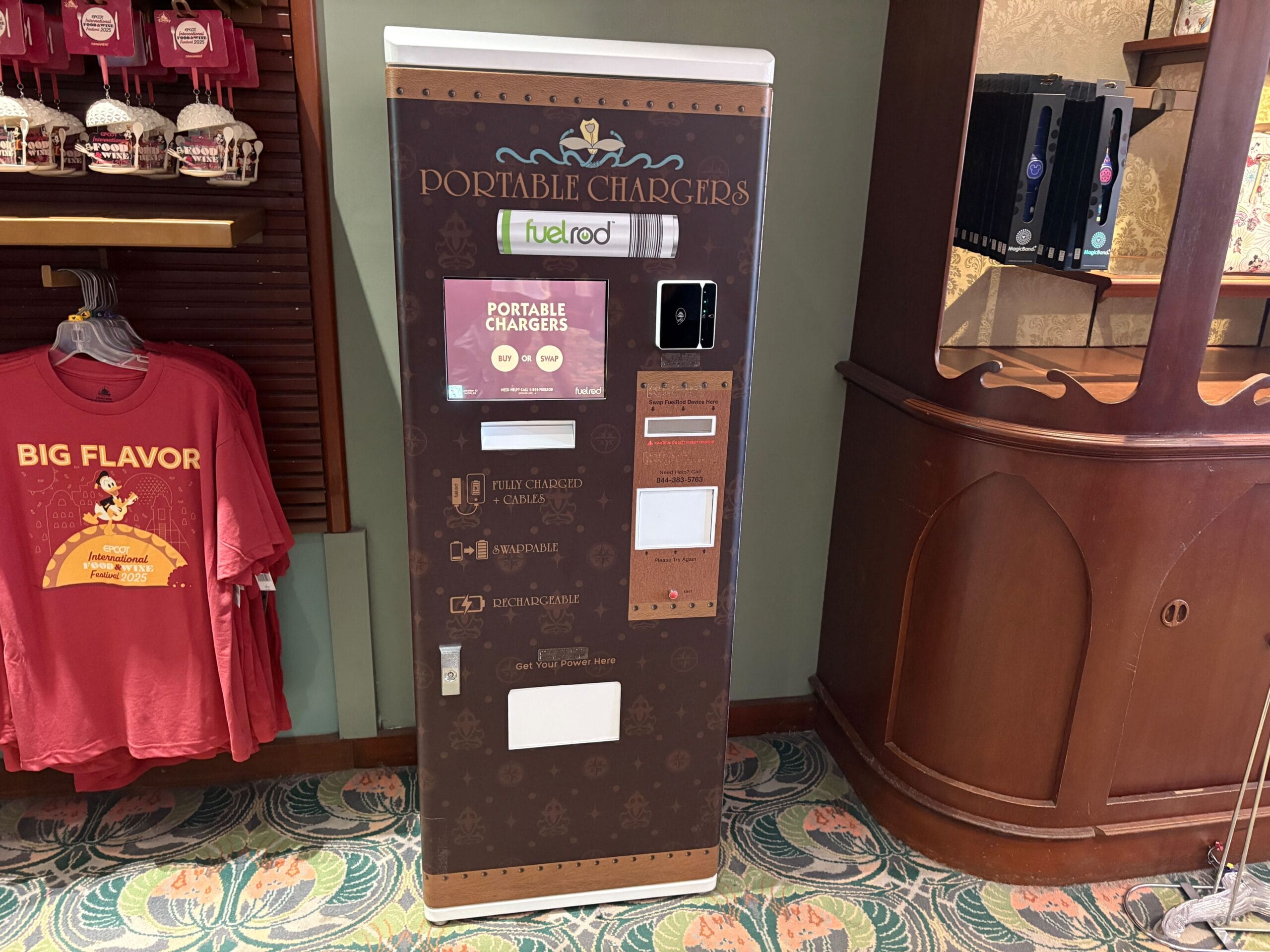 A FuelRod Kiosk indoors at Walt Disney World sits near red t-shirts and a wooden cabinet, no castle in view for comparison.