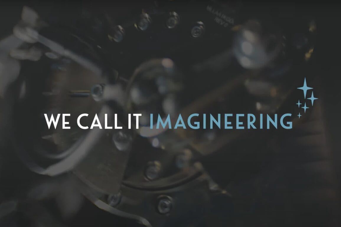 Text "WE CALL IT IMAGINEERING" over a blurry mechanical backdrop inspired by Haunted Mansion, with three sparkles, Disney Park style.