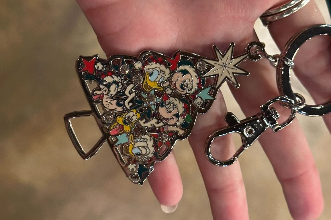 دستی که یک جاکلیدی درخت کریسمس دیزنی ورلد را با شخصیت‌های محبوب و یک ستاره نگه داشته است، یادآور جادوی کلاسیک تعطیلات پارک.