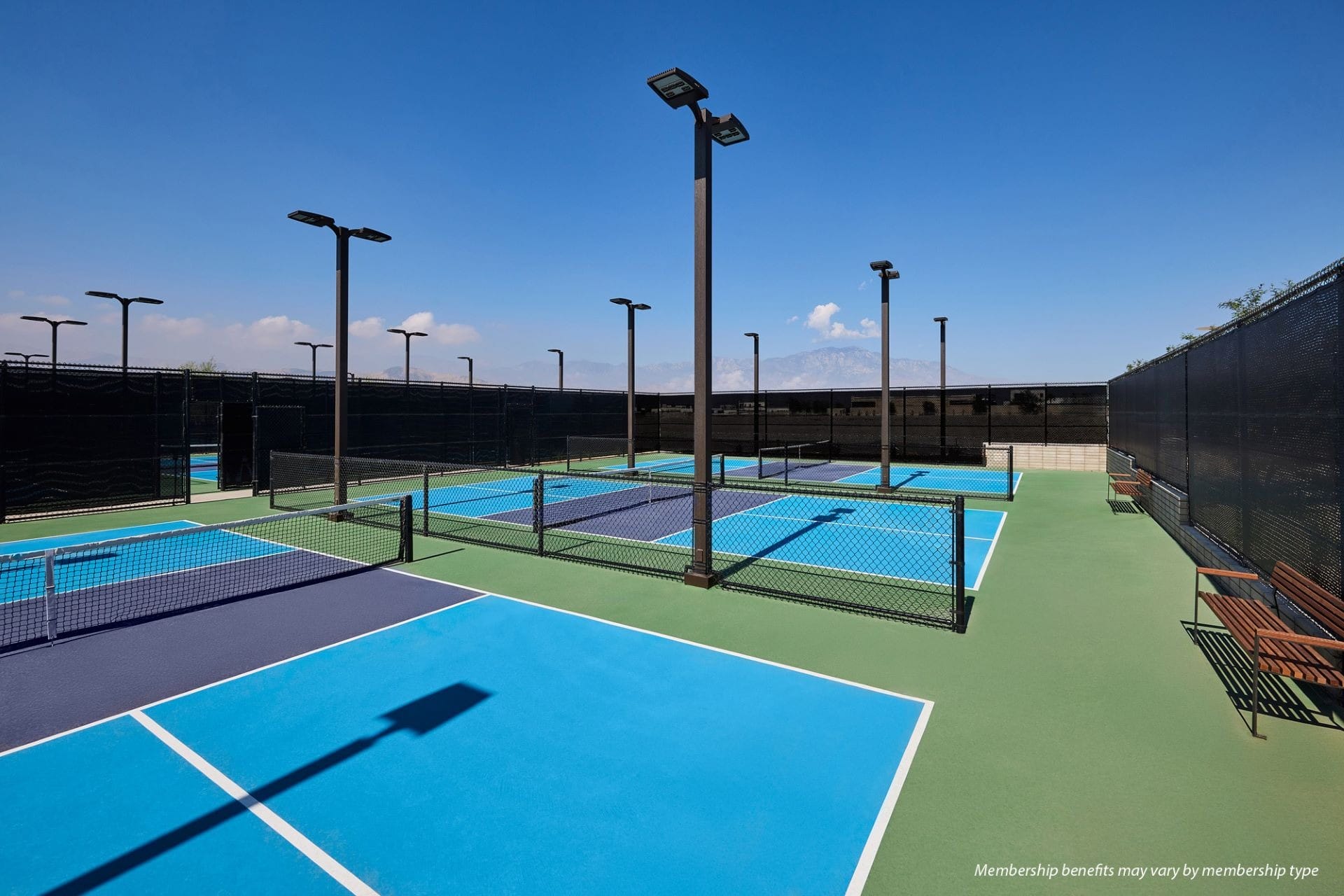 Outdoor pickleball courts at Cotino Storyliving Community, with blue-green surfaces and benches, evoke the open skies of Disney parks.