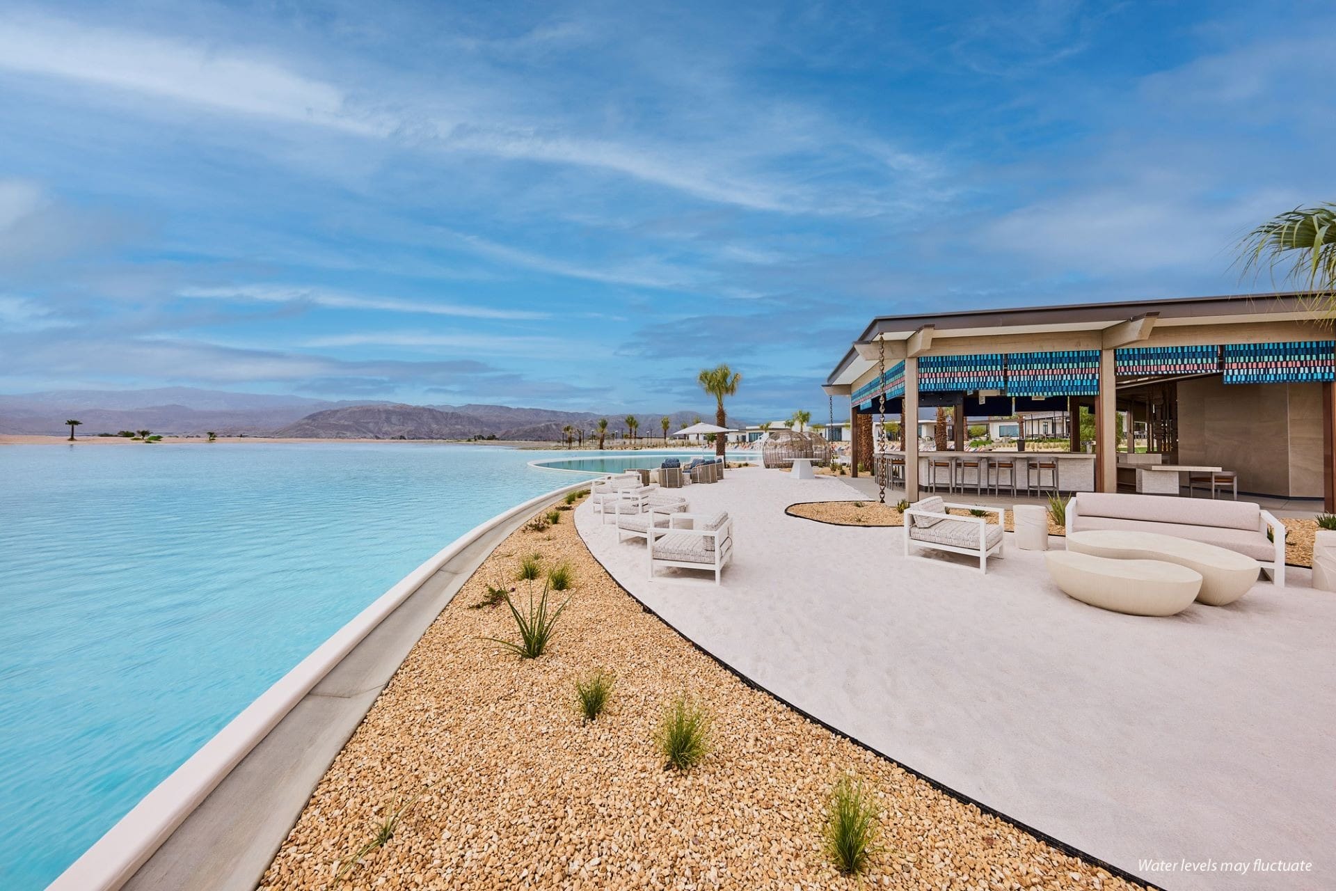 Outdoor lounge at Artisan Club in Cotino, featuring white chairs by a blue pool—no castle like those in Disneyland parks nearby.