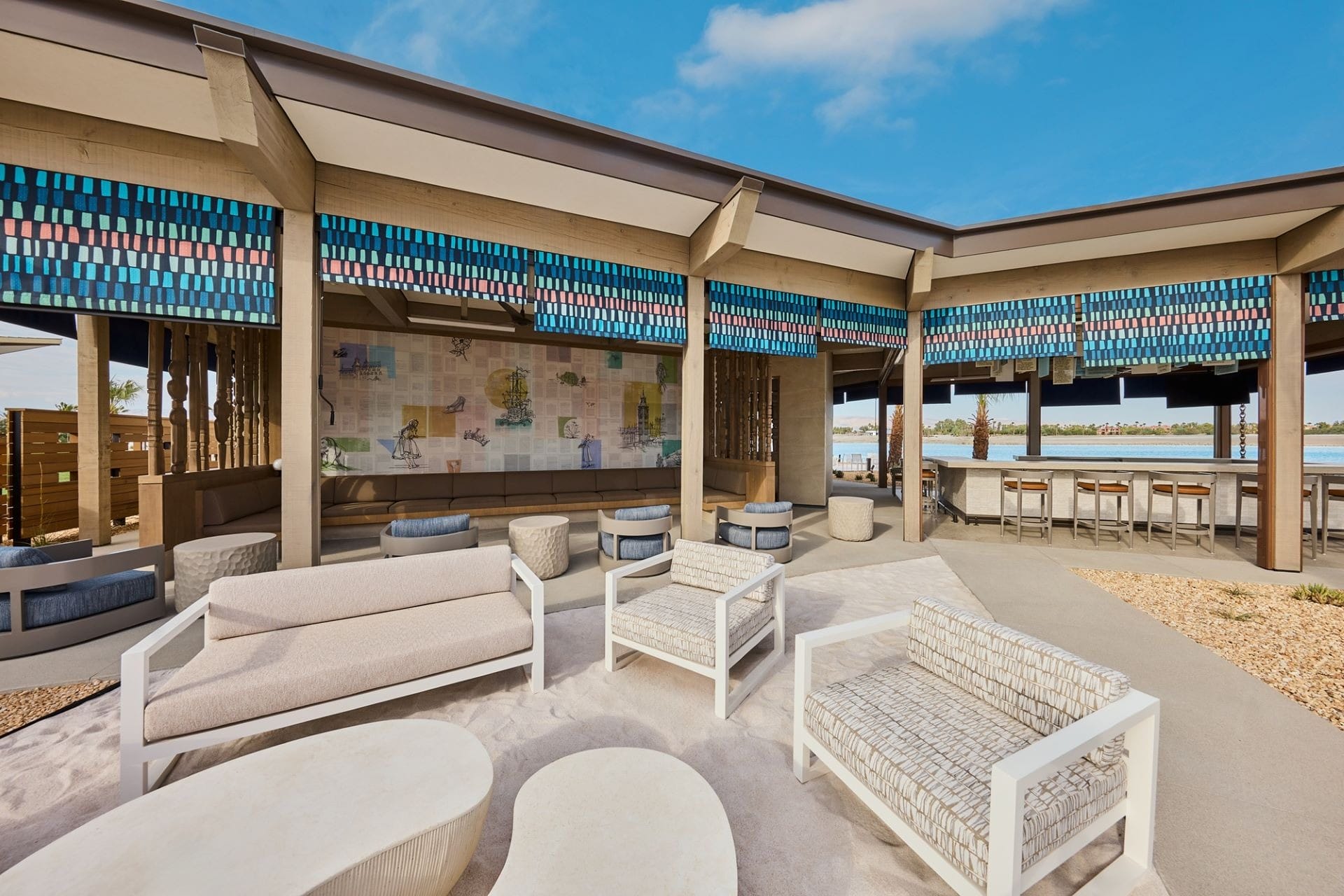 Outdoor lounge at Artisan Club in Cotino Storyliving Community, featuring modern shaded seating and water views under clear skies.