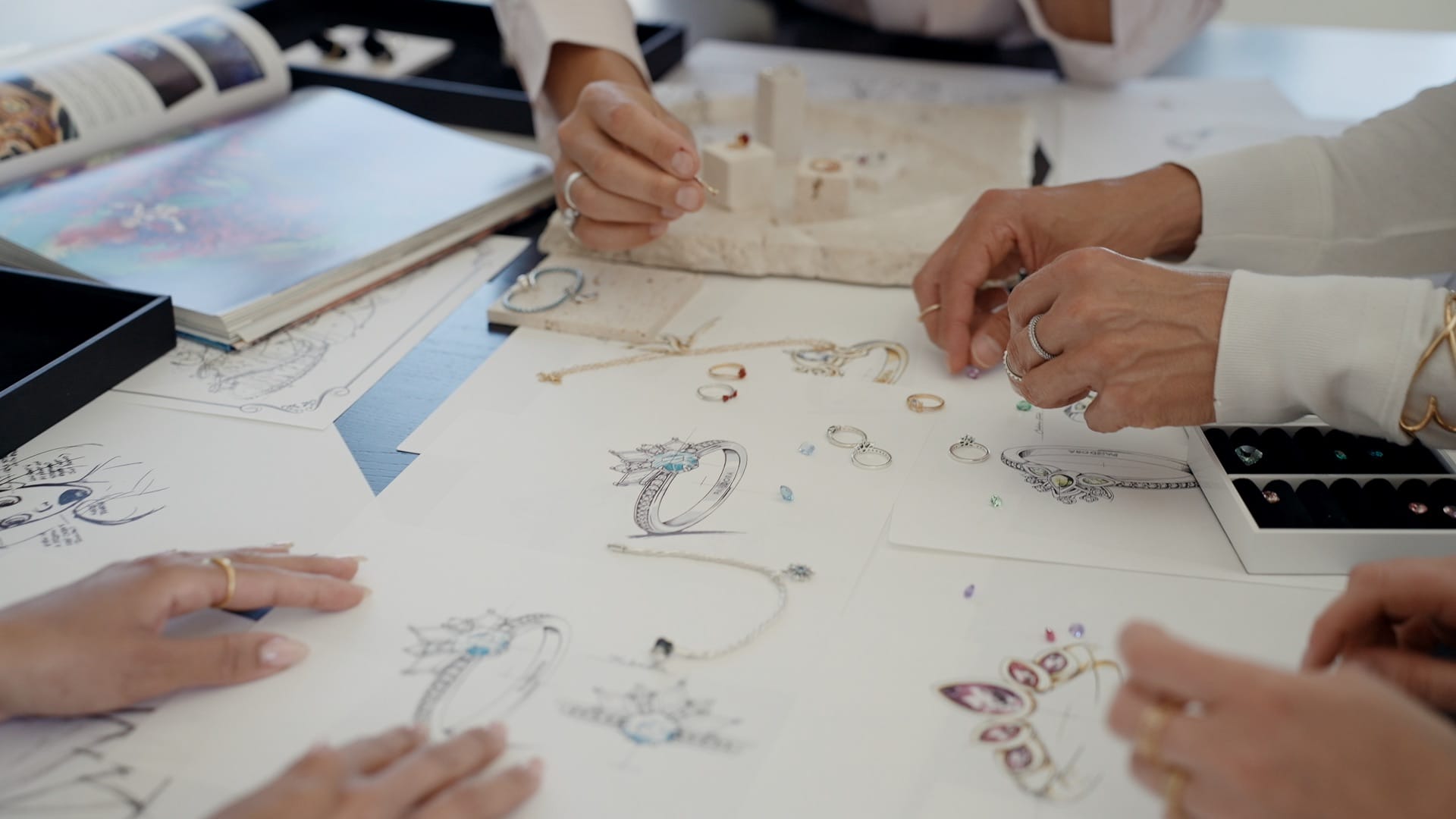 Four people design Pandora jewelry with Disney Princess-inspired rings, echoing the elegance seen in castles at Disney Parks worldwide.