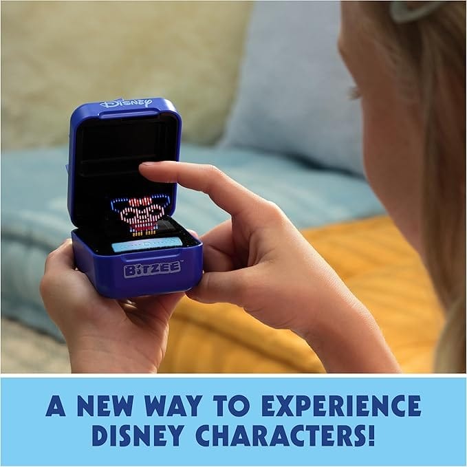 A person plays with a small digital Disney character toy in a blue "Bitzee" box, next to Disney backpacks.