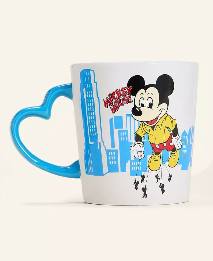 White mug with blue heart handle from Disney 2025 Holiday Collection, showing Mickey Mouse and park skyline—no castle depicted.