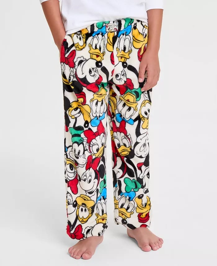 Child in Disney 2025 Holiday Collection fleece pajama pants with Mickey, Minnie, Donald, Daisy, and Pluto, no castle in view.