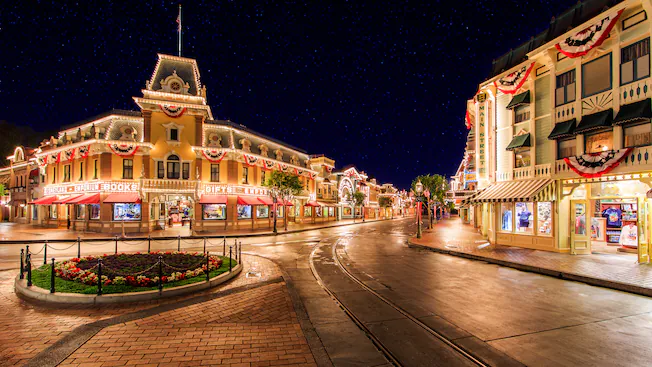 Disneyland’s Main Street sparkles at night with patriotic bunting and empty walkways lined with Princess Pins, unique to Anaheim.