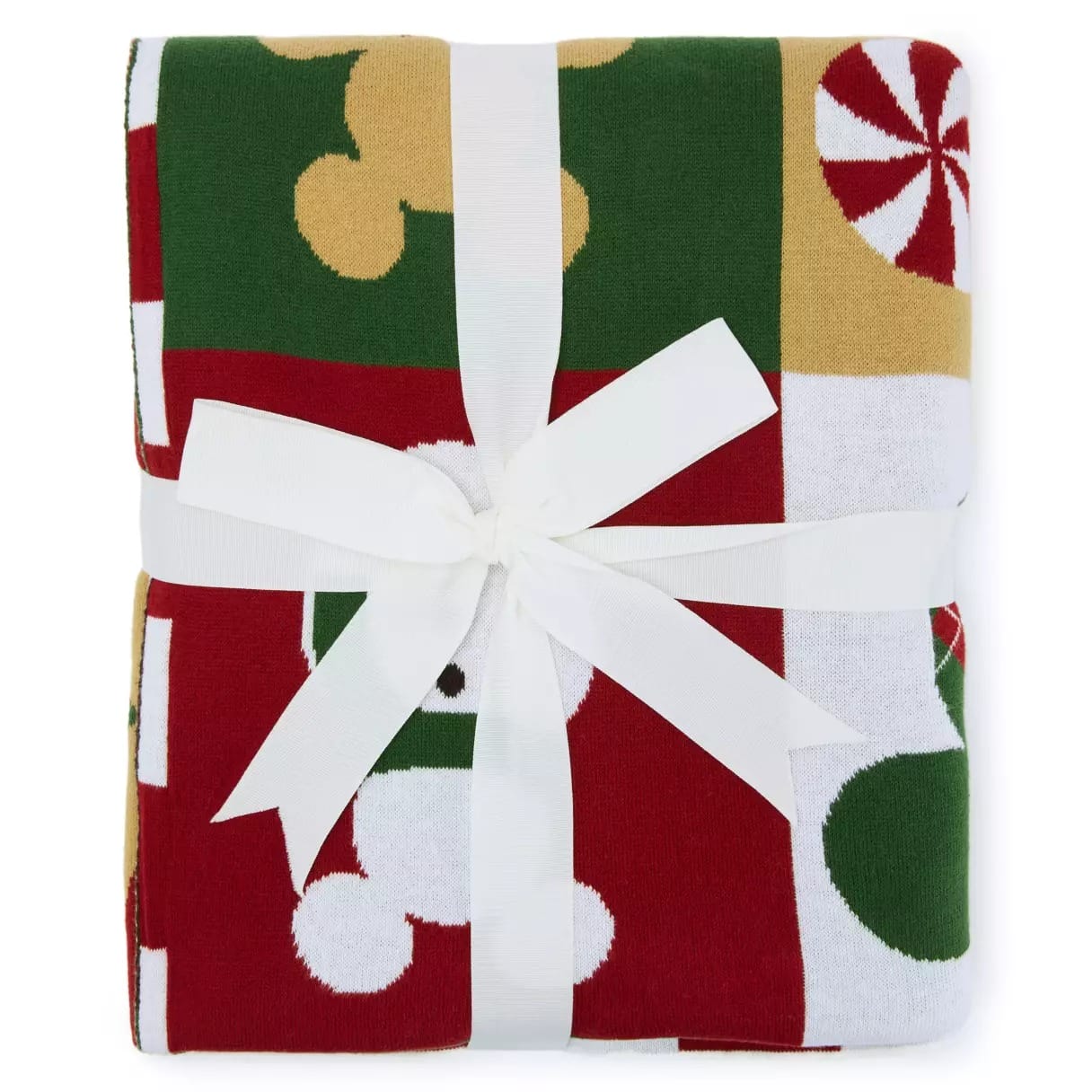 Folded holiday-themed blanket with red, green, white, and gold patterns, tied with a white ribbon bow.