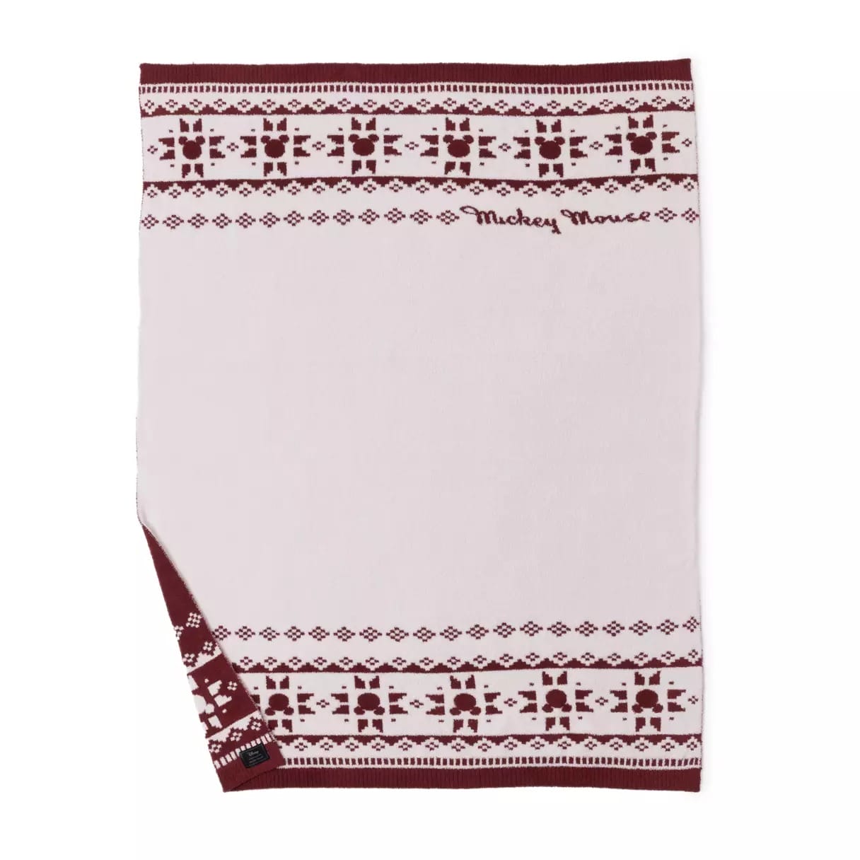 Light pink blanket with maroon Nordic patterns, "Mickey Mouse" text, and a small corner flipped to show the reverse side.