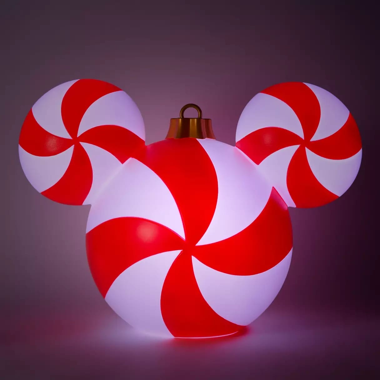 A glowing ornament shaped like Mickey Mouse, with red and white peppermint swirl patterns on each circular section.