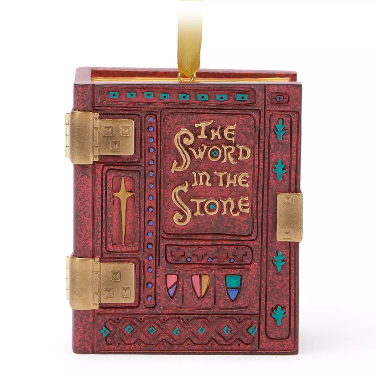 A red book ornament with gold hinges reads “The Sword in the Stone” and features shields and a sword on the cover.