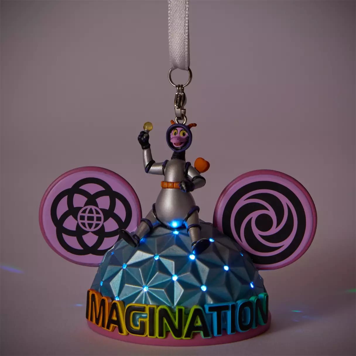 Figment ornament in a space suit sitting on a dome with lights, pink ears, and "IMAGINATION" in rainbow letters.