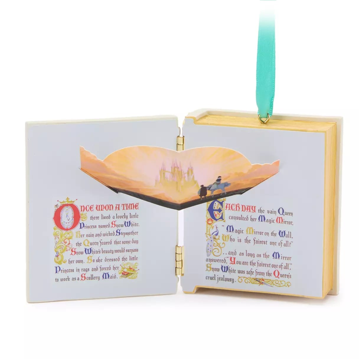 Open storybook ornament with a pop-up castle scene and fairy tale text, hanging from a green ribbon.