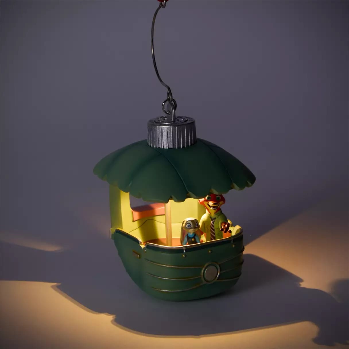 A green boat-shaped ornament with two animal characters inside, glowing warmly—perfect Disney Store Christmas merchandise.