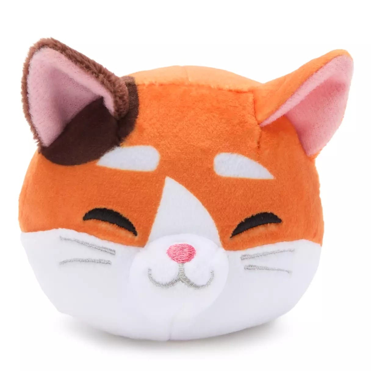 Plush toy of a smiling orange and white cat with closed eyes, pink inner ears, and a brown patch—like souvenirs at Disney parks.
