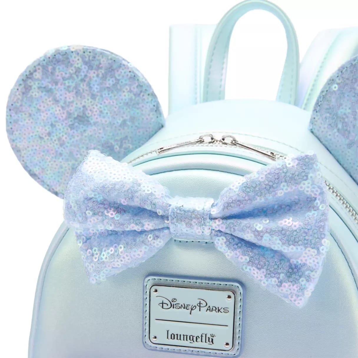 Light blue backpack with sparkly Winter Blue Minnie ears and bow, Disney Parks Loungefly label on front, seen at Disney parks.