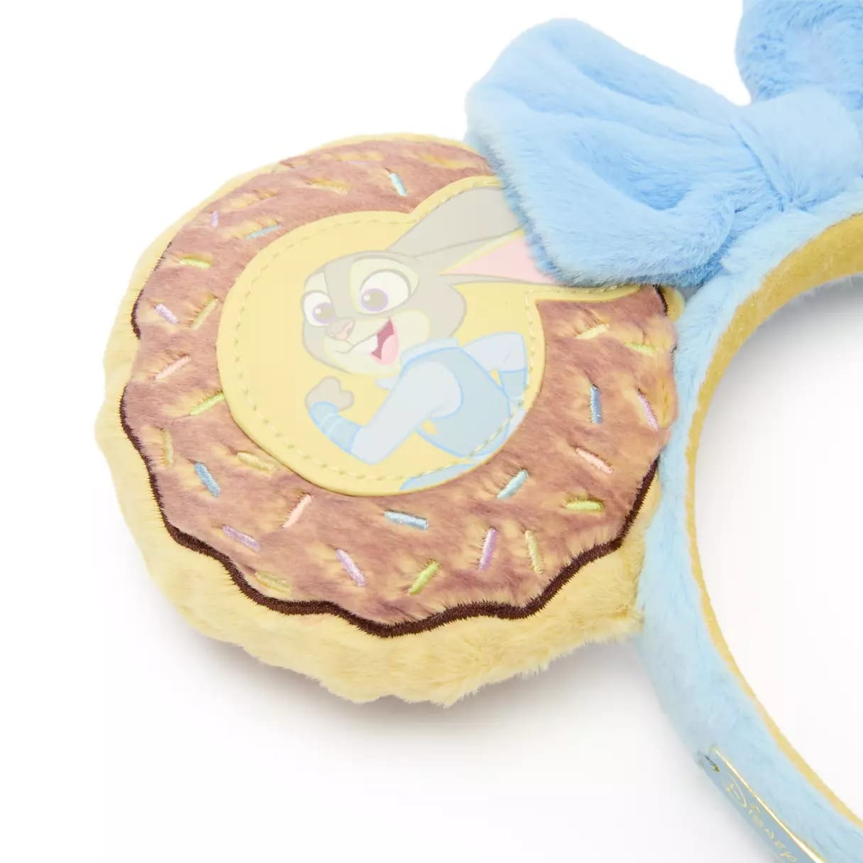 A soft, donut-shaped Mickey ear headband featuring Judy Hopps from Zootopia and a blue bow, sold at Disney Parks worldwide.